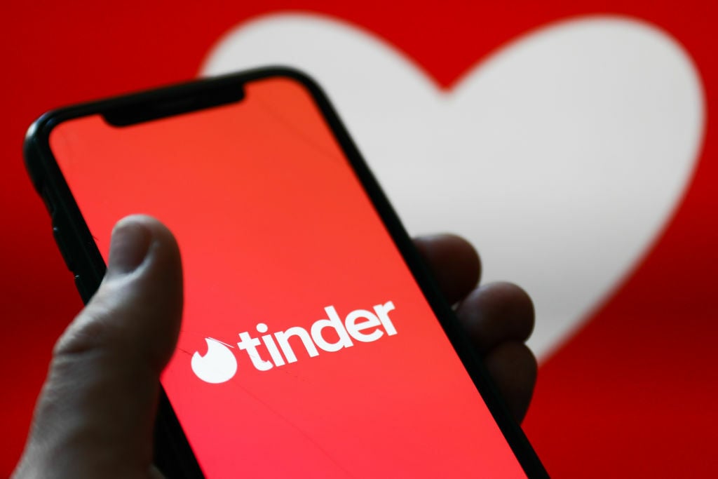 Someone holds an iPhone with the Tinder app open 