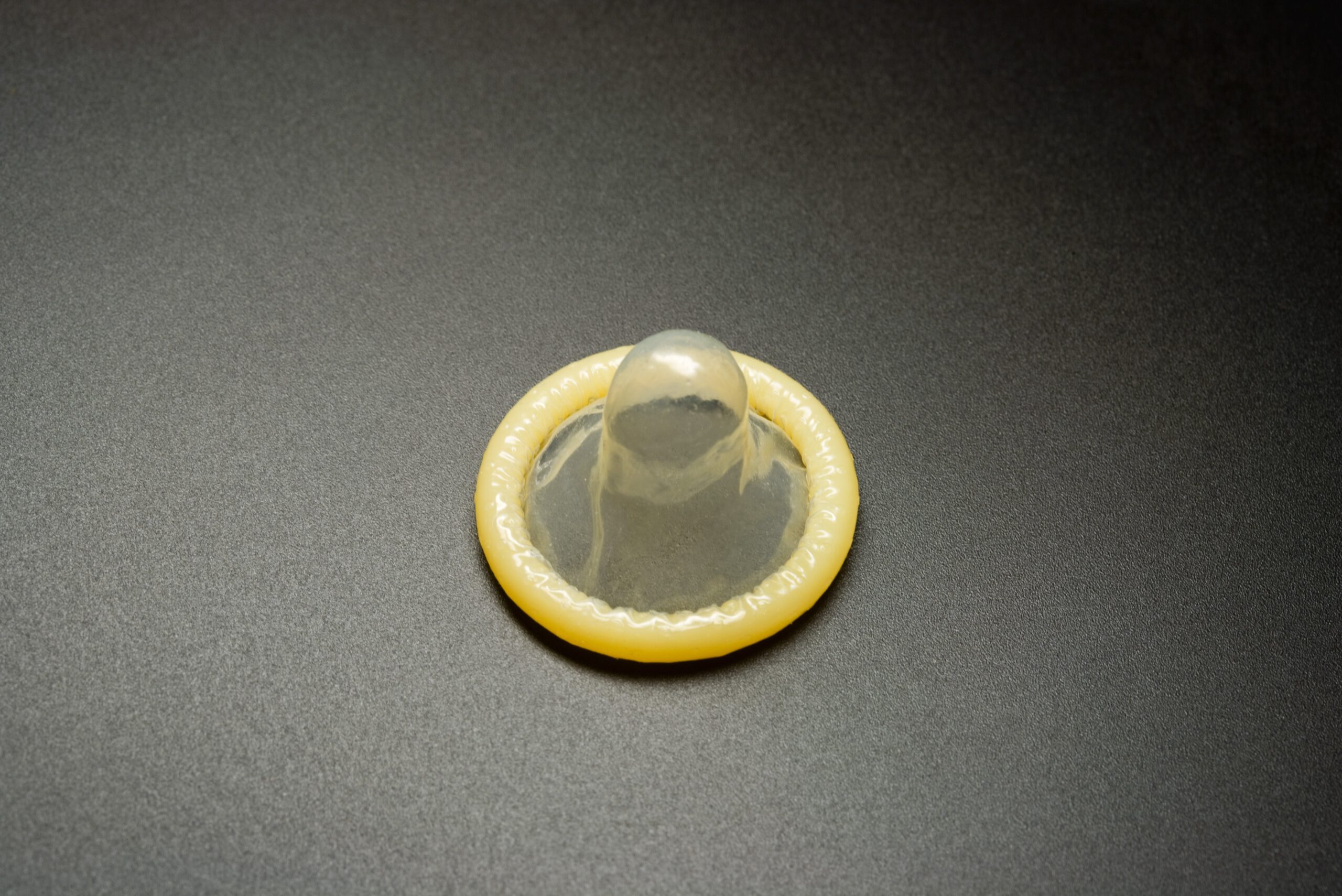 yellow condom on black background