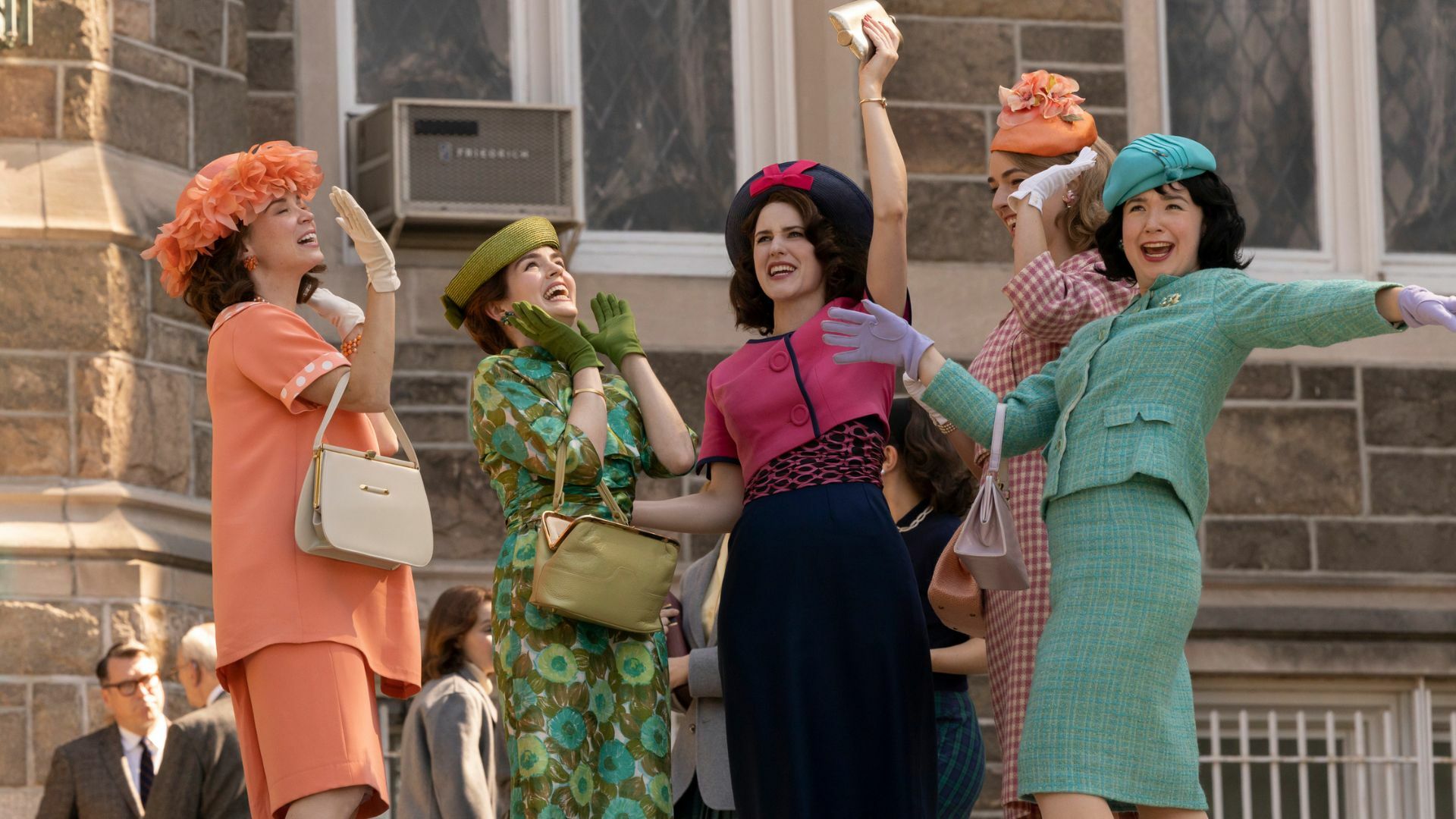 Women in vibrant '60s attire celebrate. 