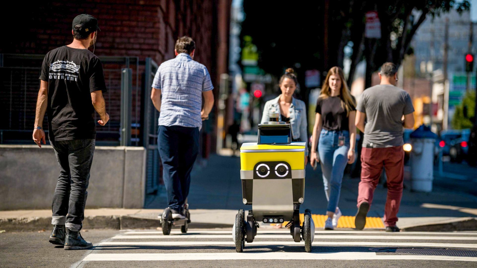 A robot on the sidewalk surrounded by people.