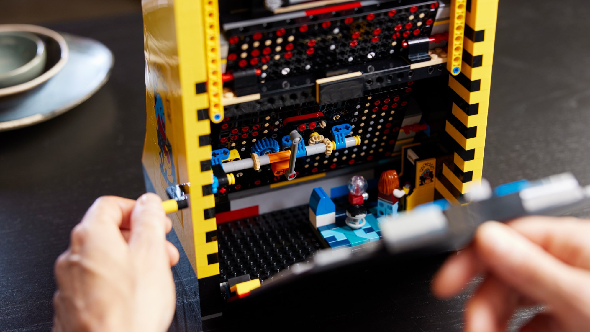 Inside the back of a Lego 'Pac-Man' machine showing a tiny Lego figure playing Pac-Man.