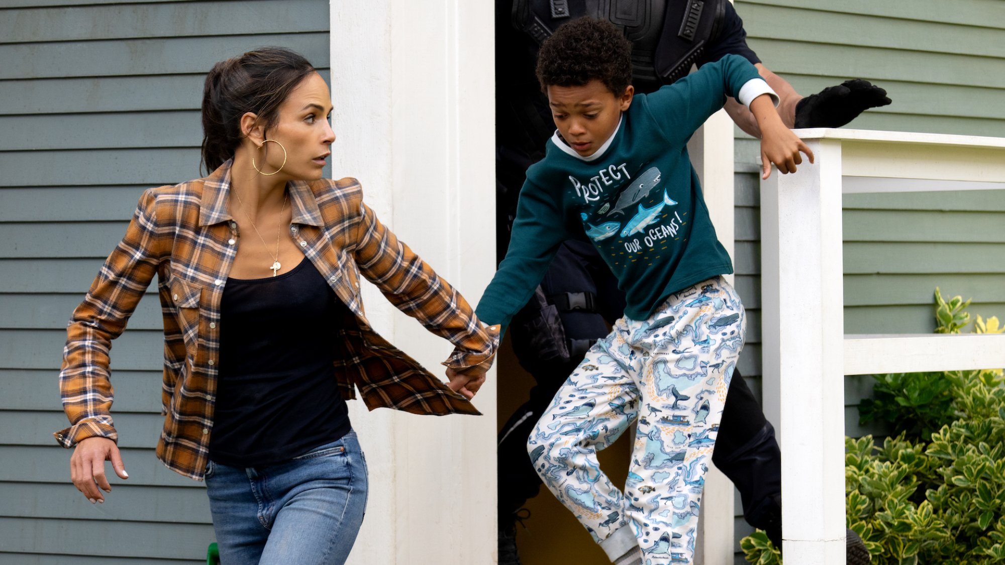 Jordana Brewster takes Leo Abelo Perry by the hand running out of a house in the film "Fast X."