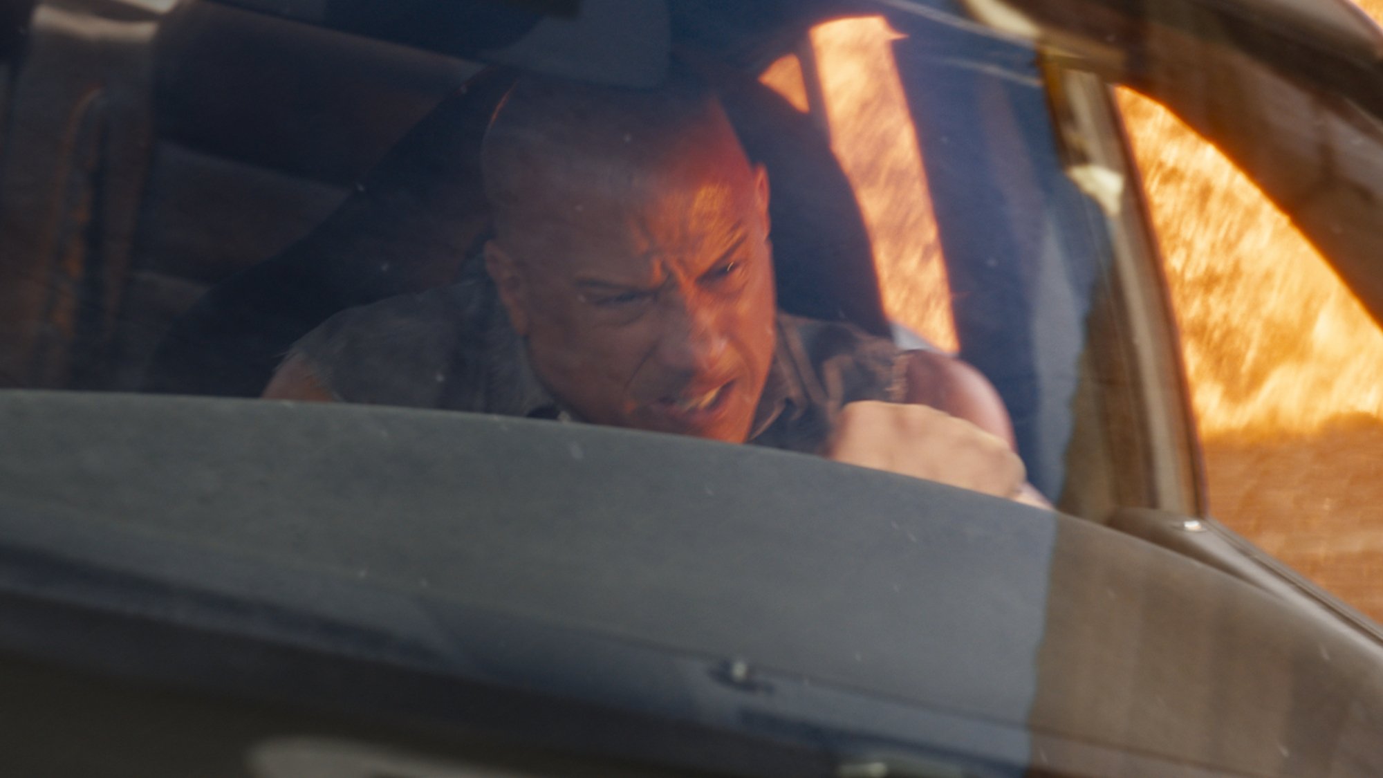 Vin Diesel drives a car away from fire in the film "Fast X"