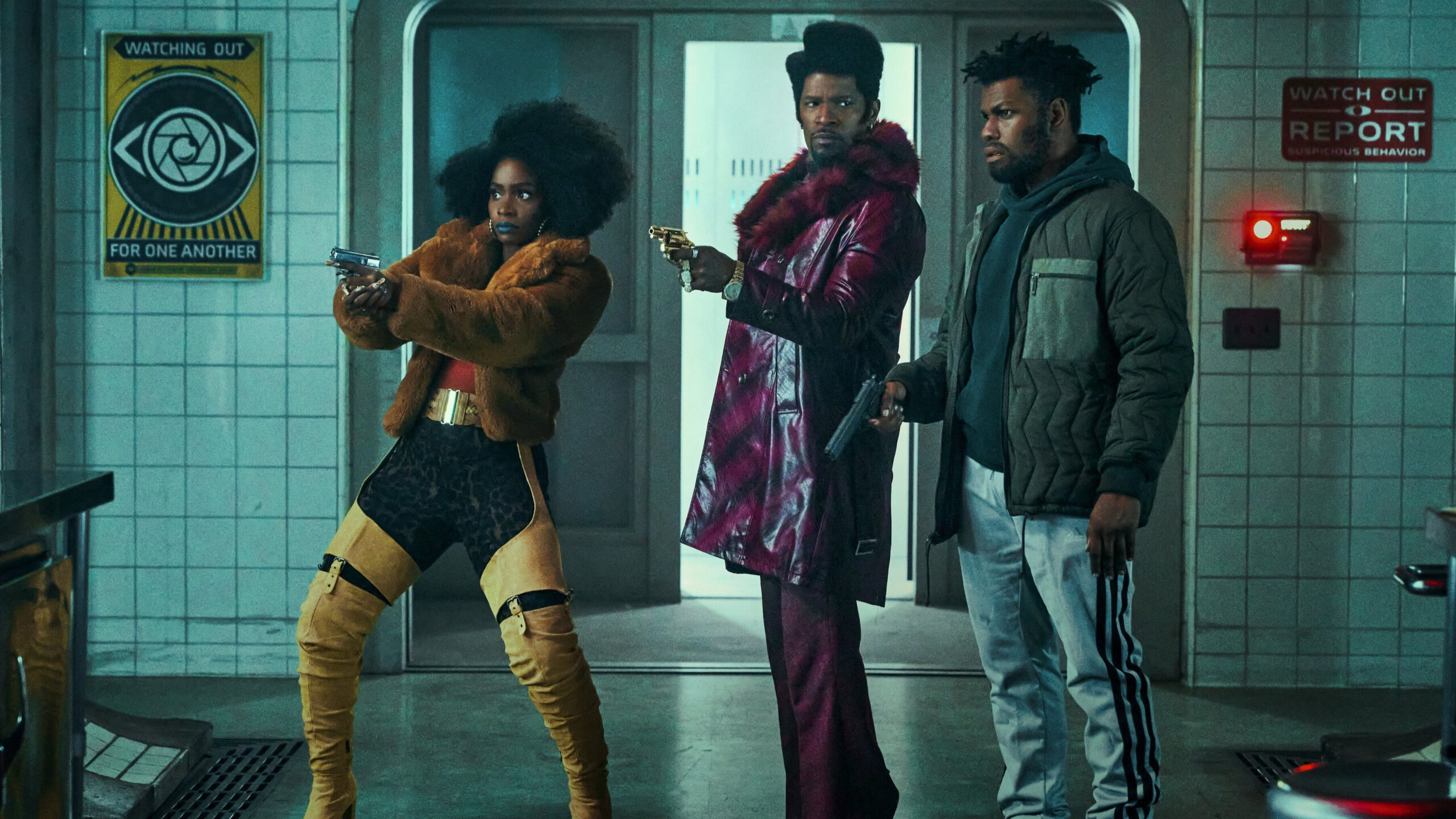 Three adults wearing colorful, '70s style clothes barge into a basement with guns. 