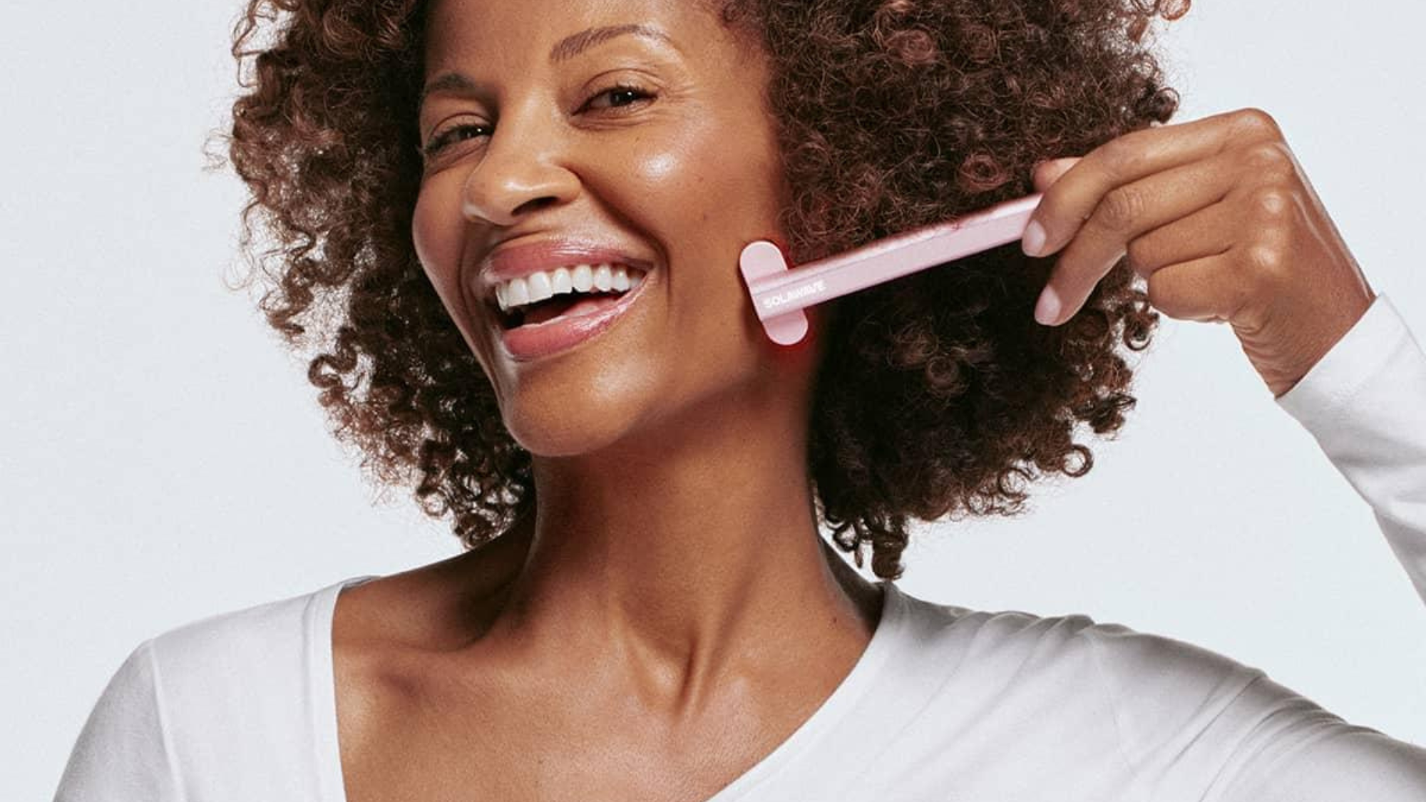 woman smiling and using a solawave skin wand 