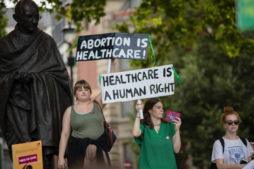 Pro-abortion protesters hold placards which read 