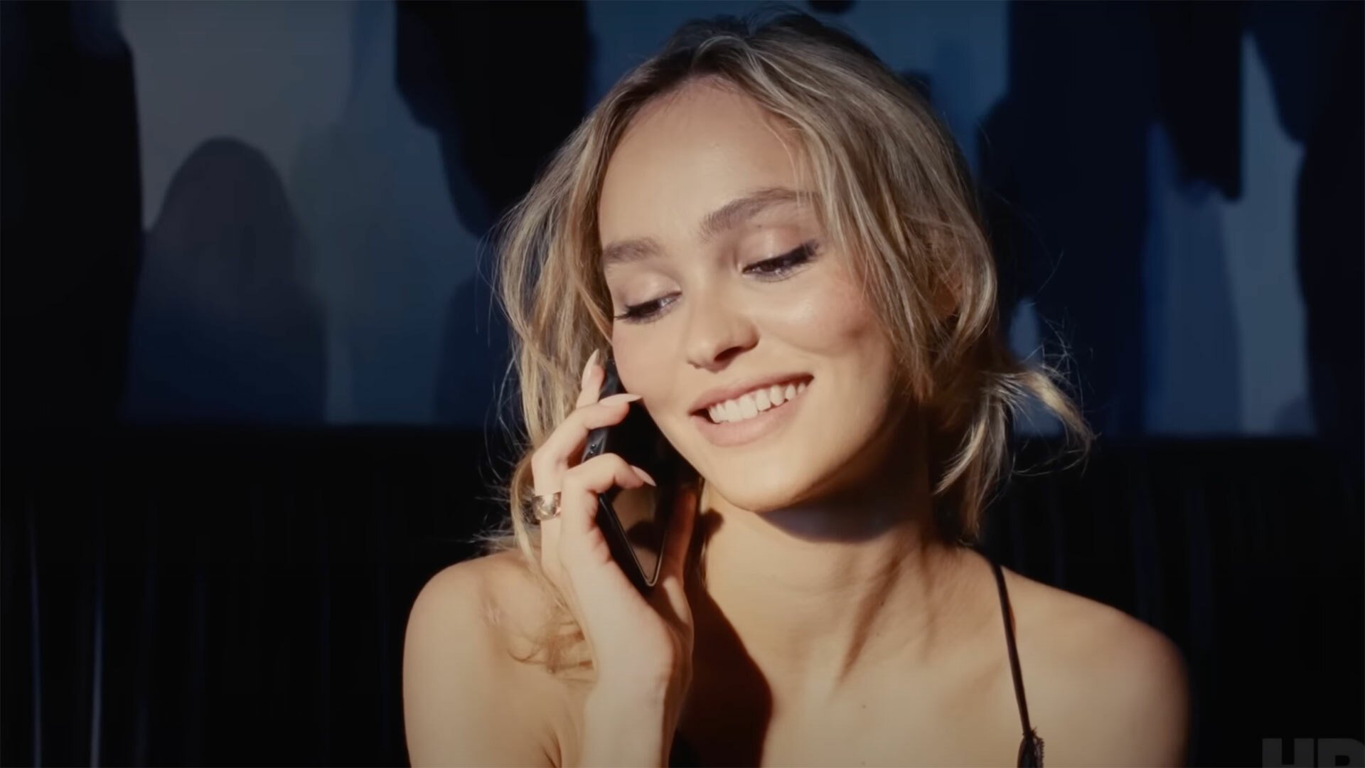 A smiling woman speaks on the phone.