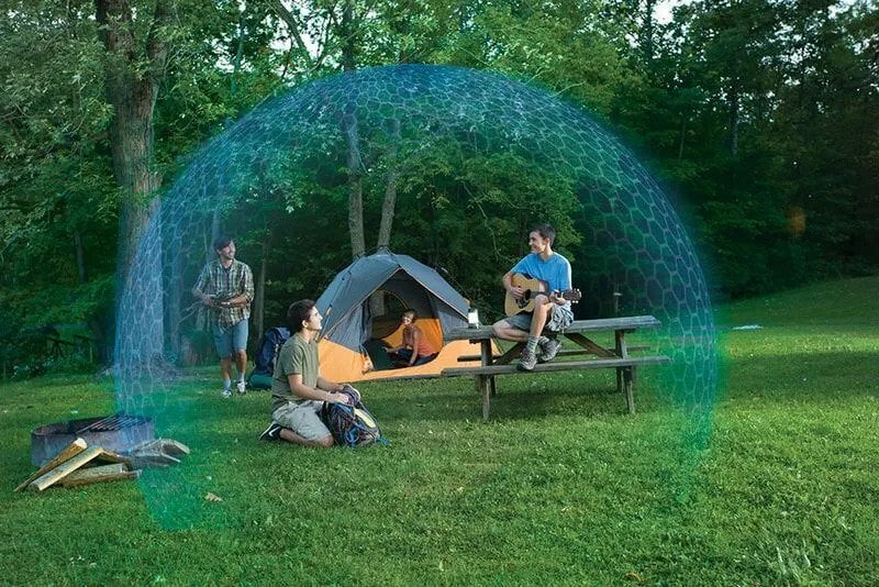 People walking or sitting around their camp setup in the woods with a blue, forcefield-like bubble around them