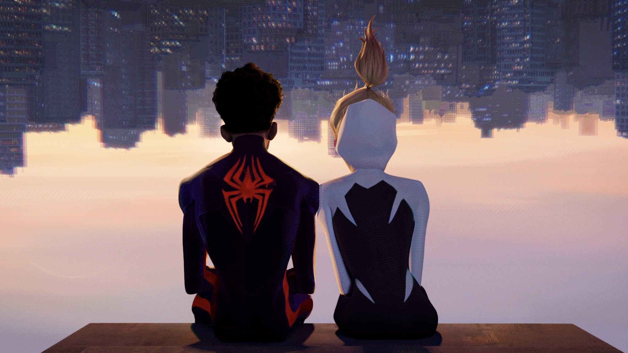 Miles Morales in his red and black Spider-Man and Gwen Stacy in her white and black Spider-Woman suit sit upside down on a building ledge.