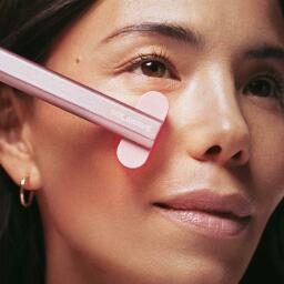 a close-up of a woman using a solawave radiant renewal skincare wand on her face