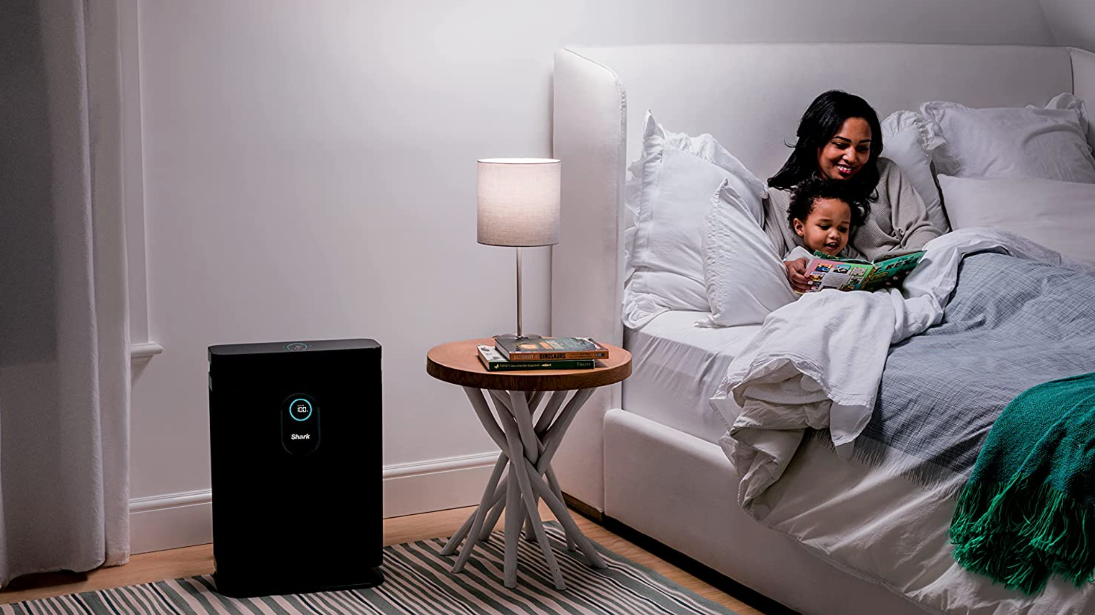 mom reading to son in bedroom, shark air purifier to the left
