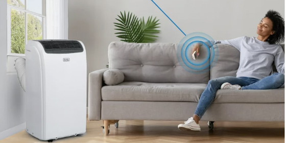 The BLACK+DECKER 8,000 BTU Portable Air Conditioner shown in a living room, with a woman enjoying its powers while resting on the couch.