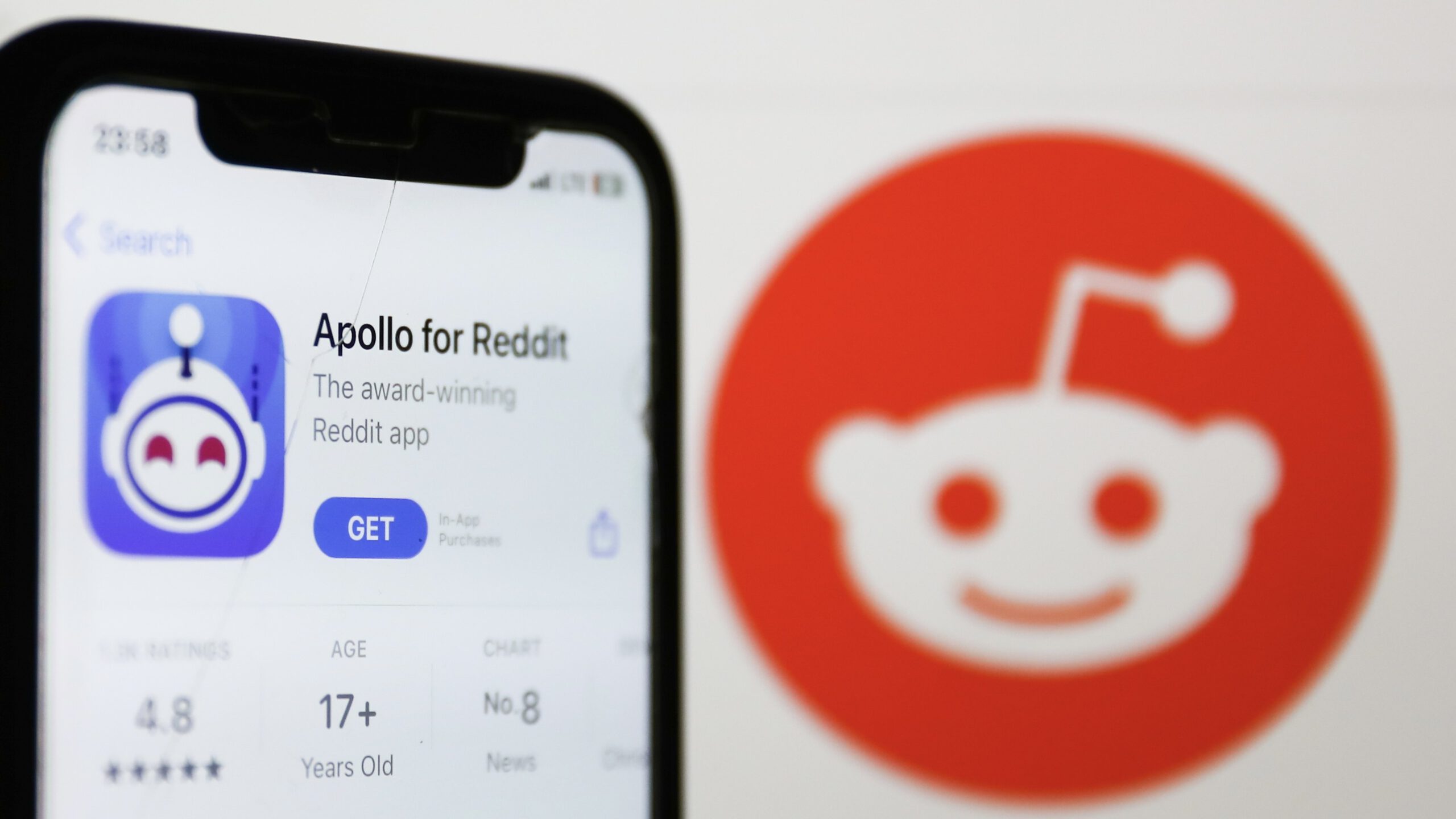 A phone with the app store open to Apollo for Reddit against a white backdrop with the orange Reddit logo.