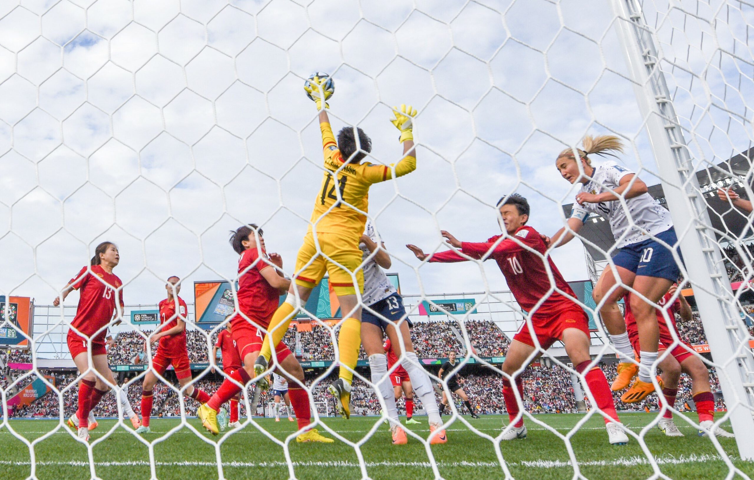 Two teams battle for a soccer ball in front of a white net.