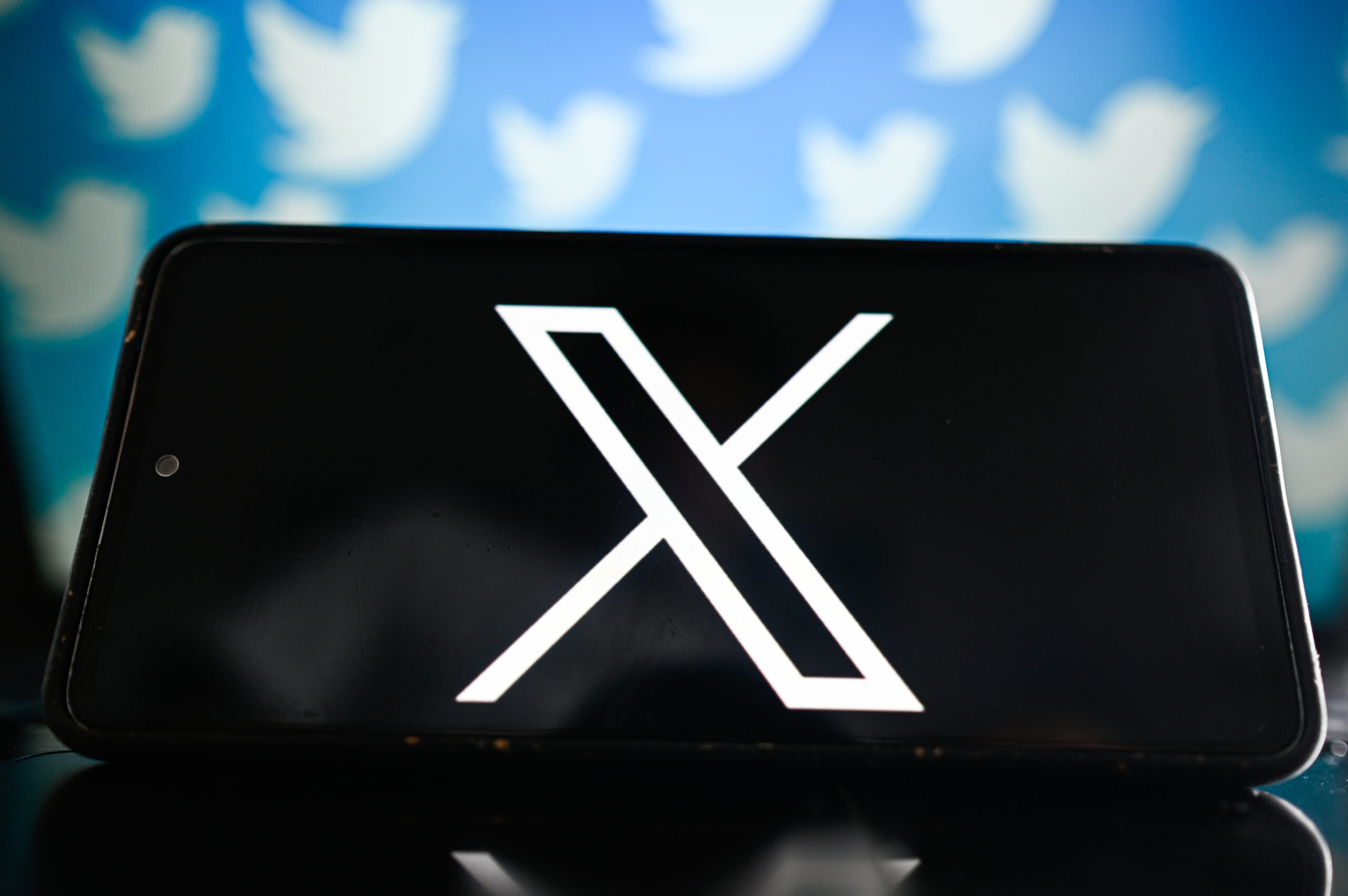 X logo with Twitter blue bird logos behind it