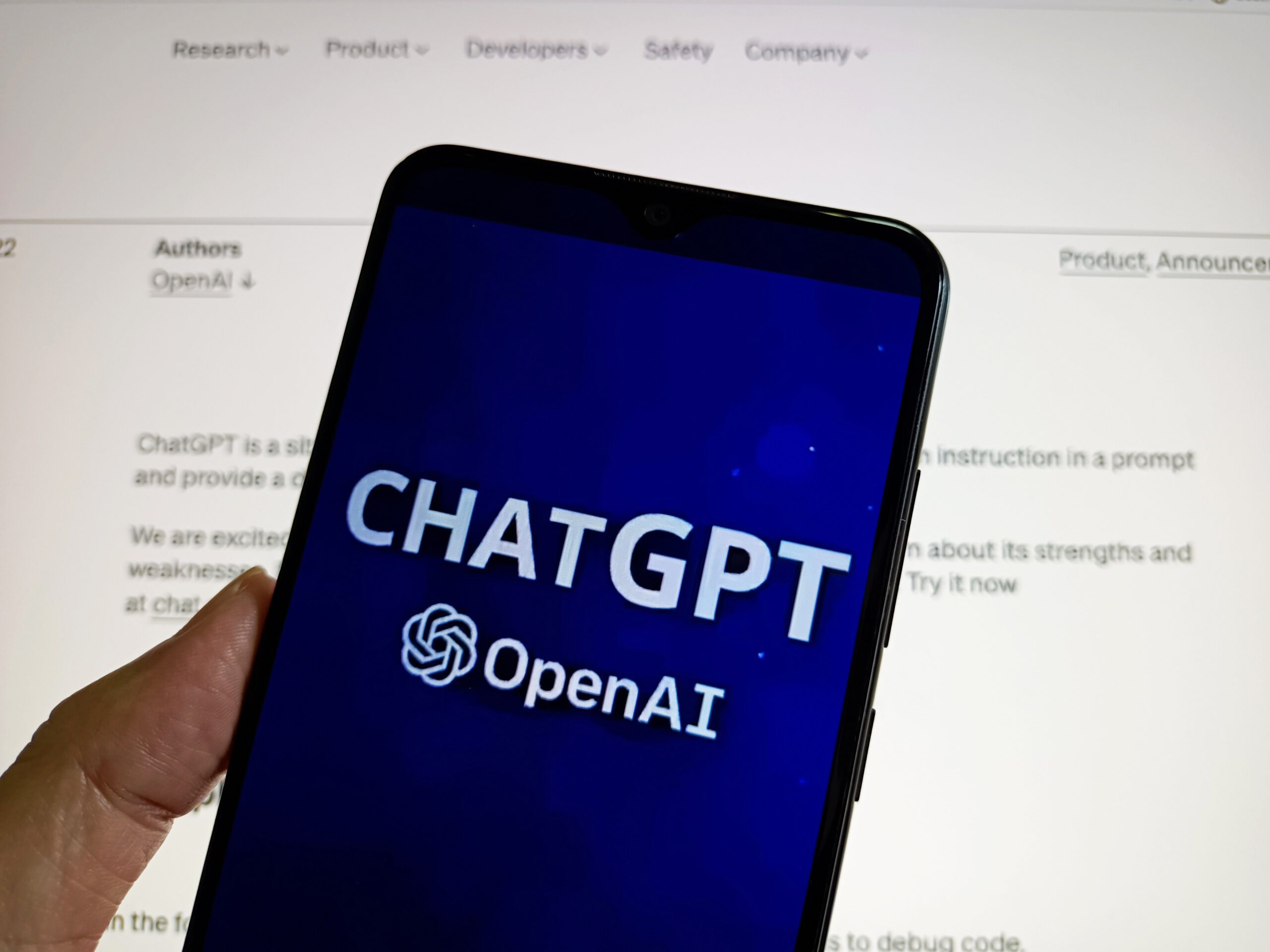 a phone with the ChatGPT logo and a screen with some text in the background
