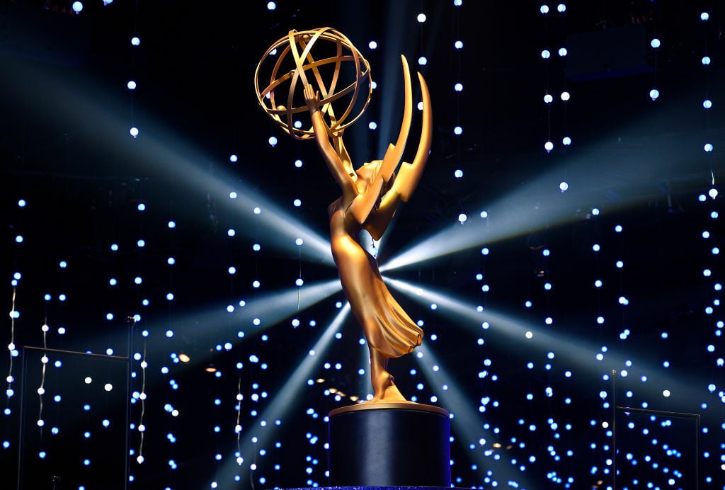 A large gold Emmy Award statue in front of a background of fairy lights.