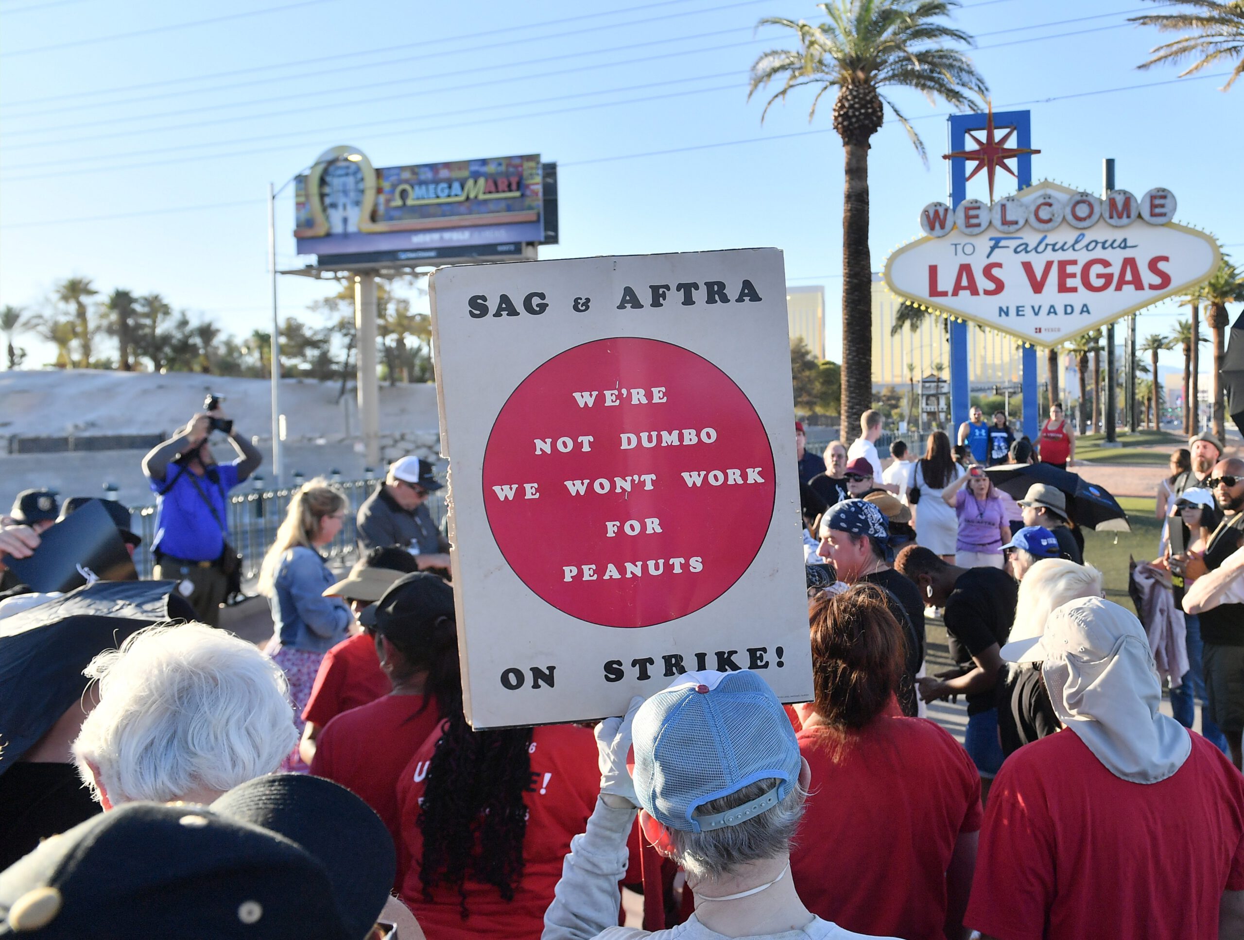 SAG-AFTRA and WGA workers gather in Las Vegas. A person holds a sign that reads, 