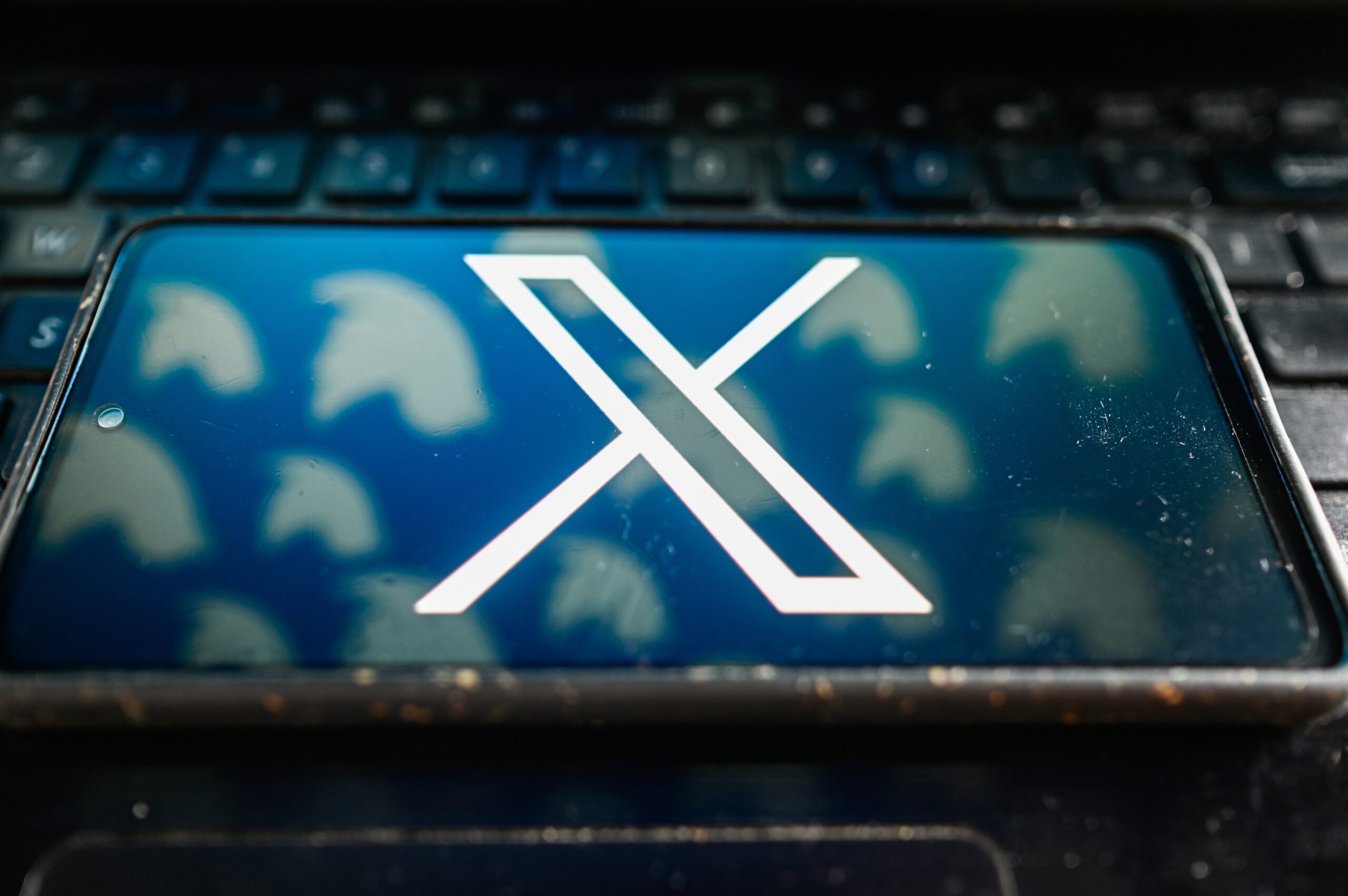 X logo on mobile device over Twitter bird logos