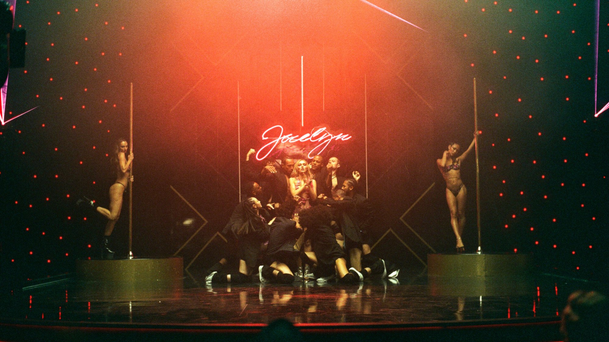 A group of dancers perform on a dimly lit stage. 