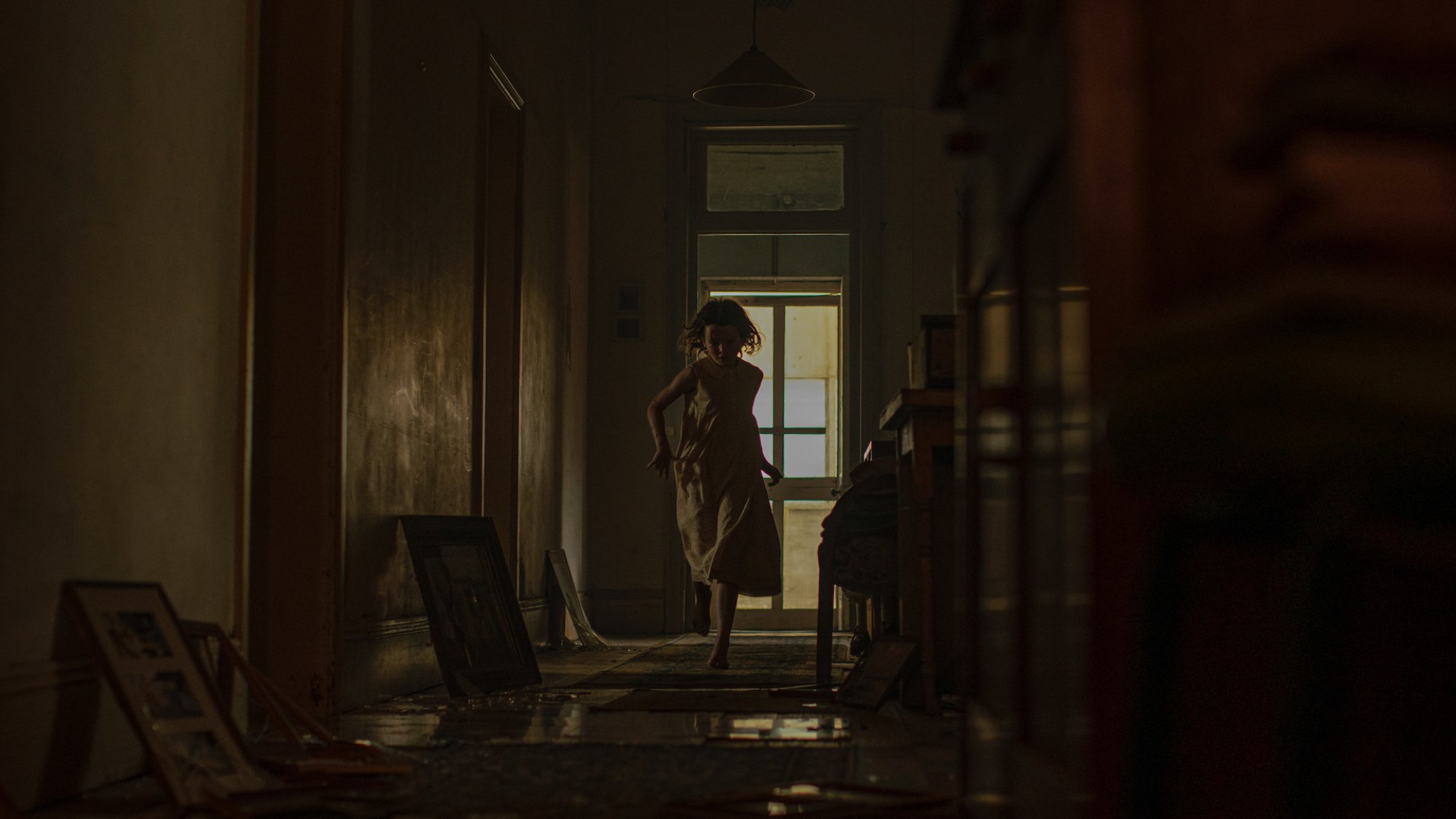 A girl runs through a dark house in the film "Run Rabbit Run"