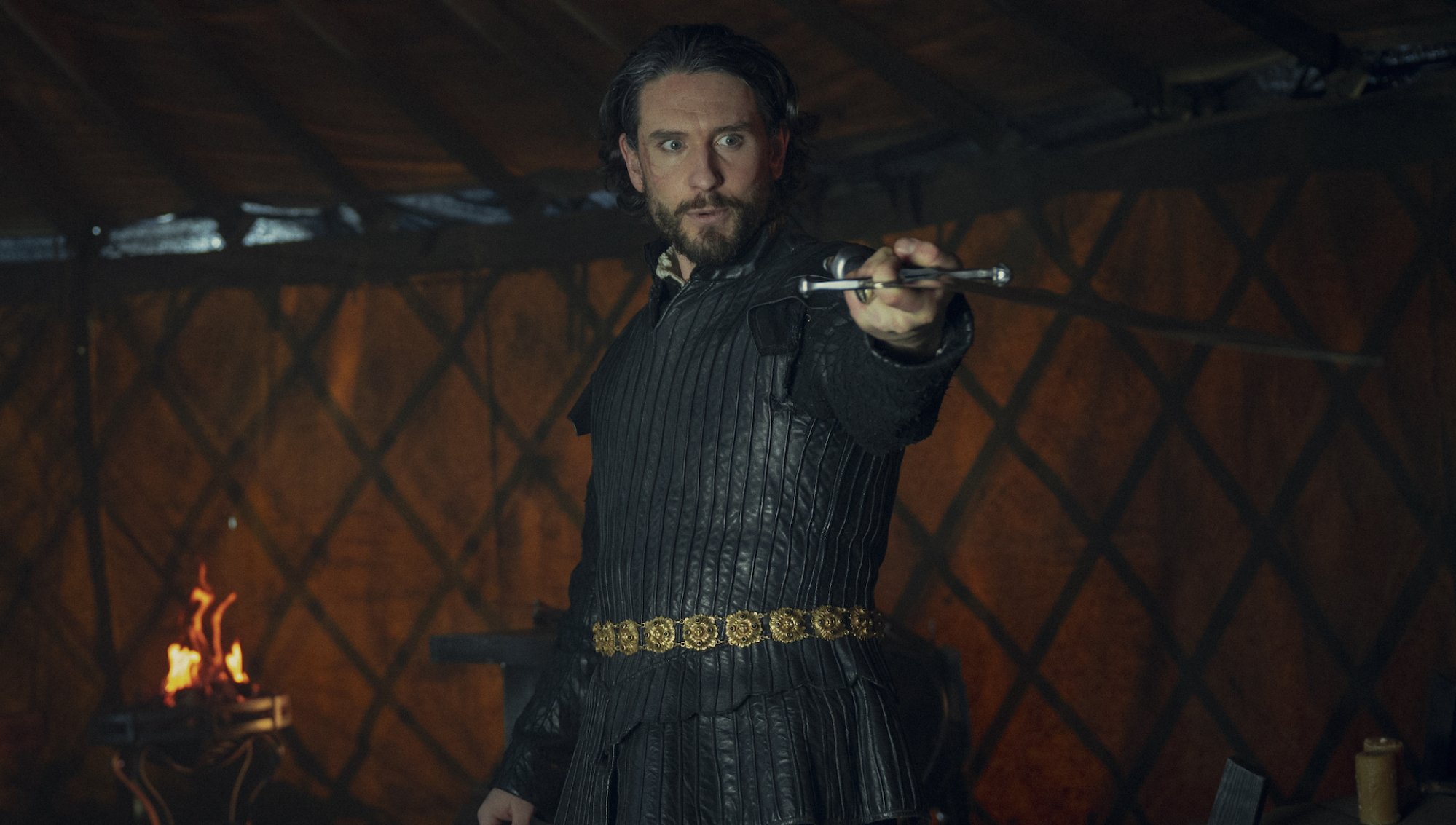 Bart Edwards, in black armor and holding a sword in front of him, in "The Witcher.
