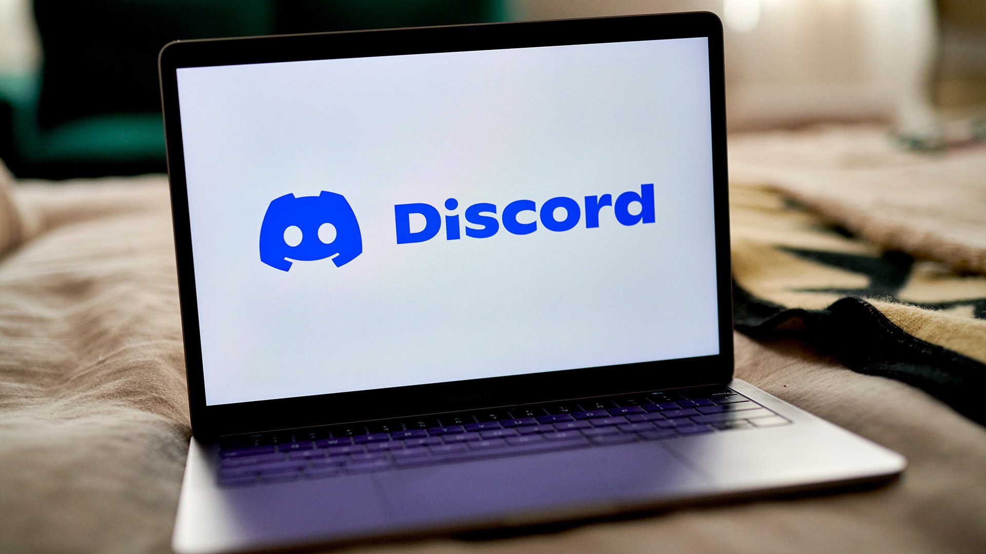The Discord logo is visible on a laptop screen.