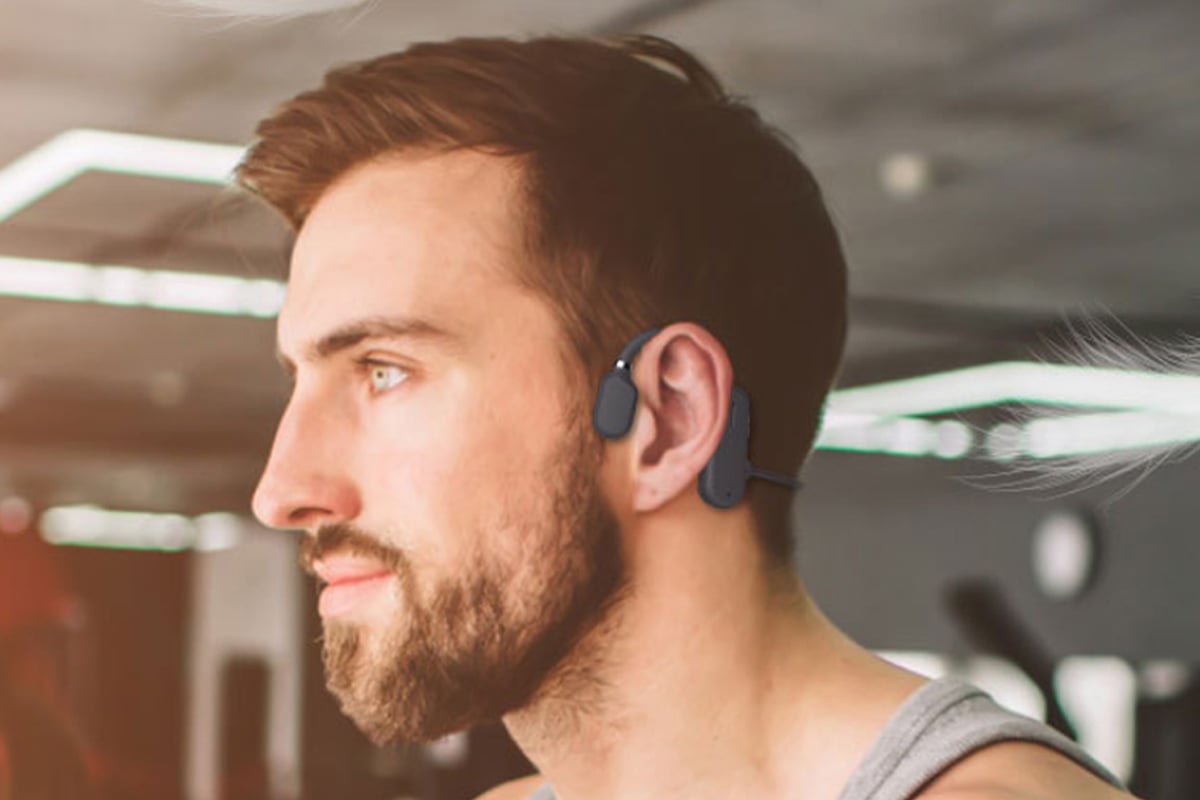 A man wearing open-ear conduction headphones while looking ahead.