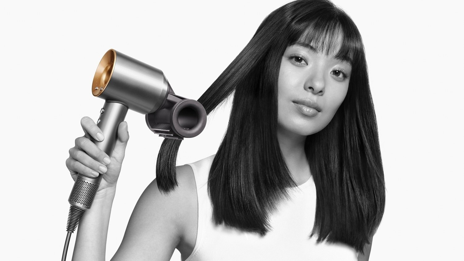 women uses dyson supersonic with flyaway smoother attachment to blow dry her hair