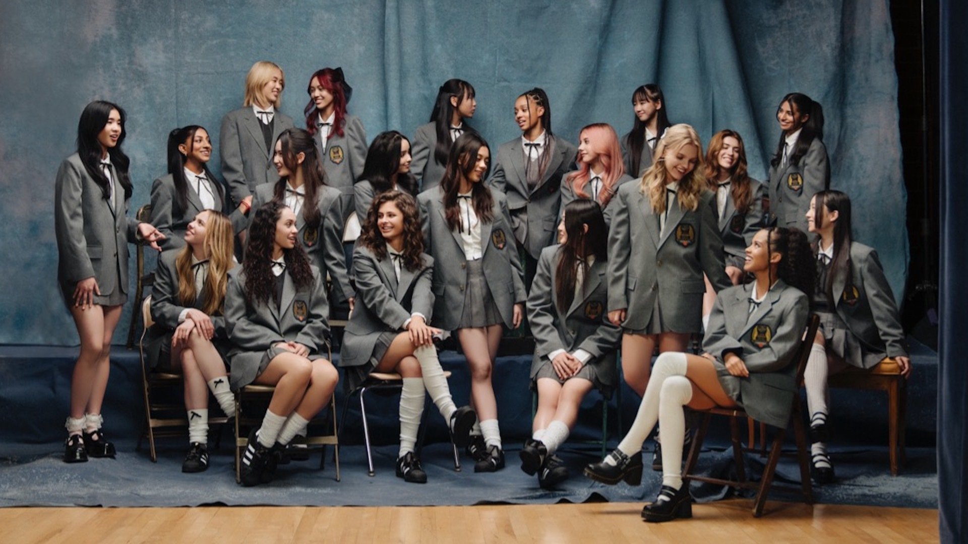 20 contestants in school uniforms pose for a promotional shot to advertise the search for a global girl group.