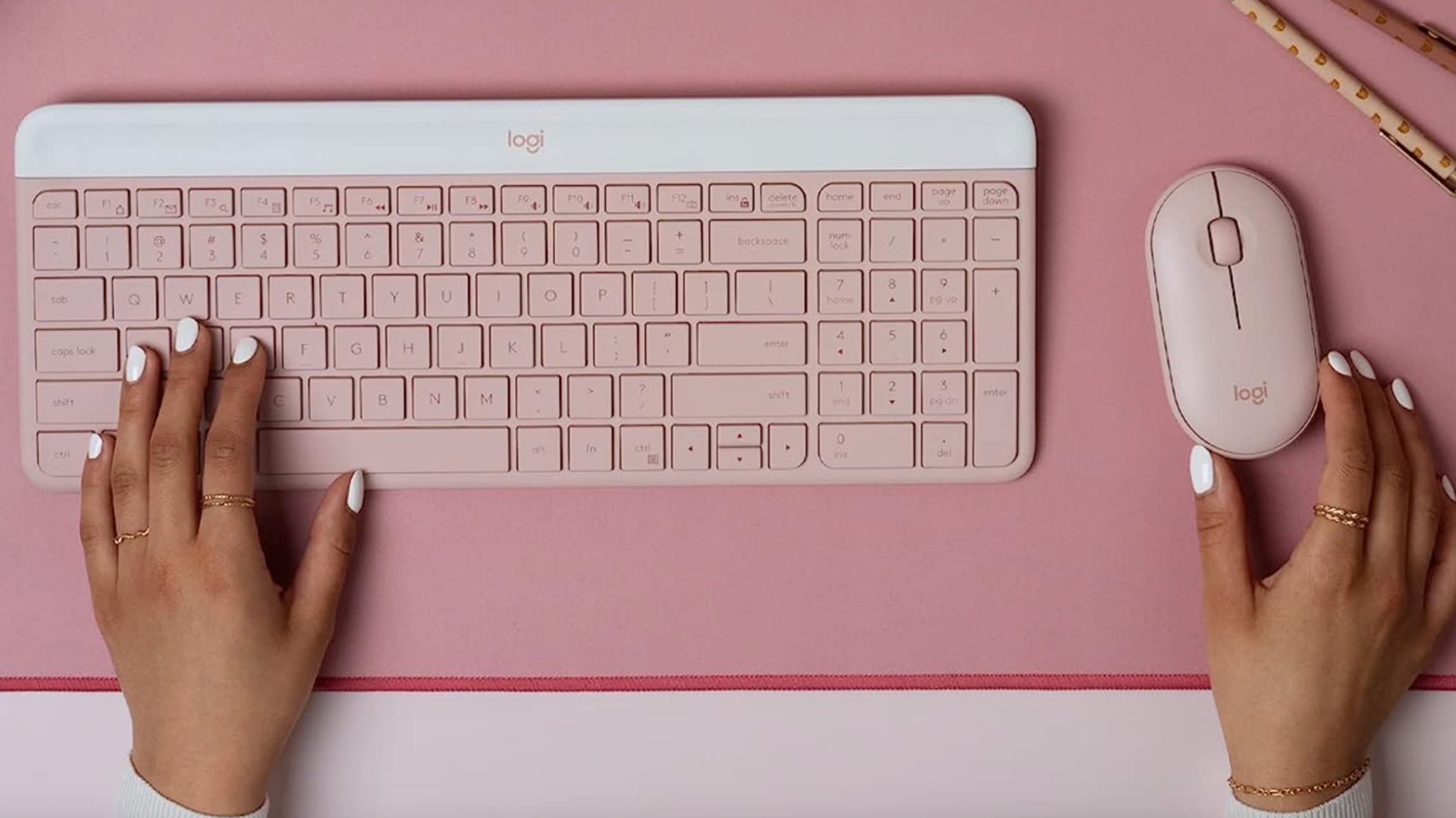 pastel pink wireless mouse and keyboard with hands on each item