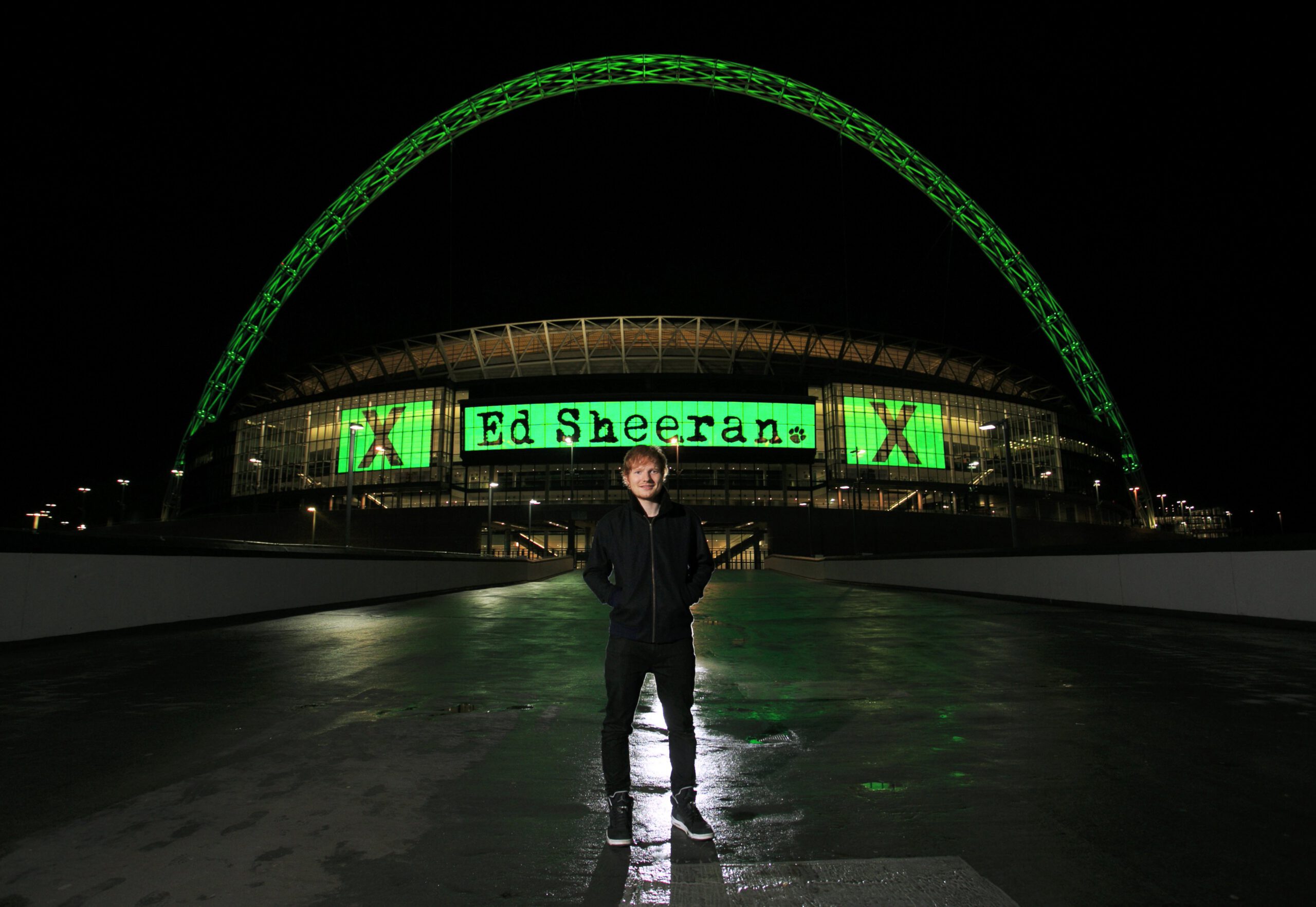 Ed Sheeran in front of Wembley Stadium, which is decked out with the letter X as that was the name of the album Sheeran was promoting when the photo was taken in 2014