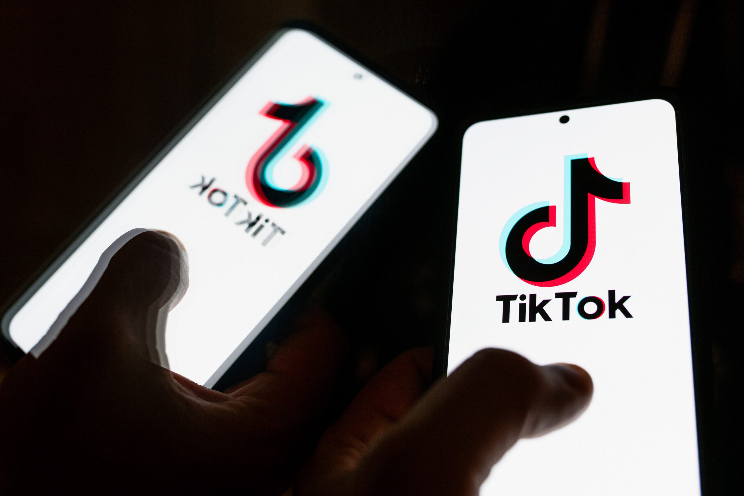 A iPhone screen displaying the TikTok logo reflected in a mirror.