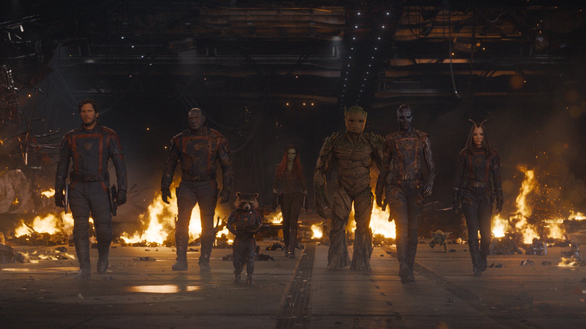 A group of superheroes walk out of a burning building. 