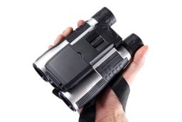 HD Digital Camera Binoculars in someone's hand, over a white background