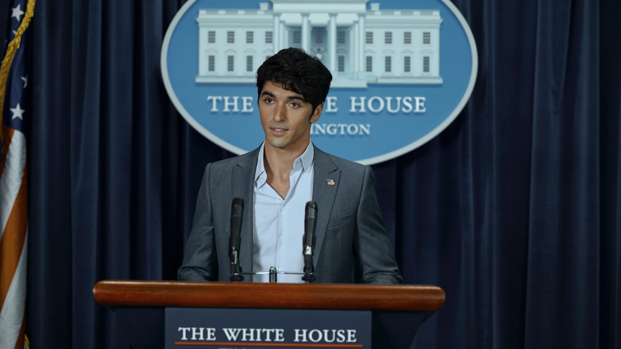 A dark-haired man in a suit speaks at a podium in the White House press room.