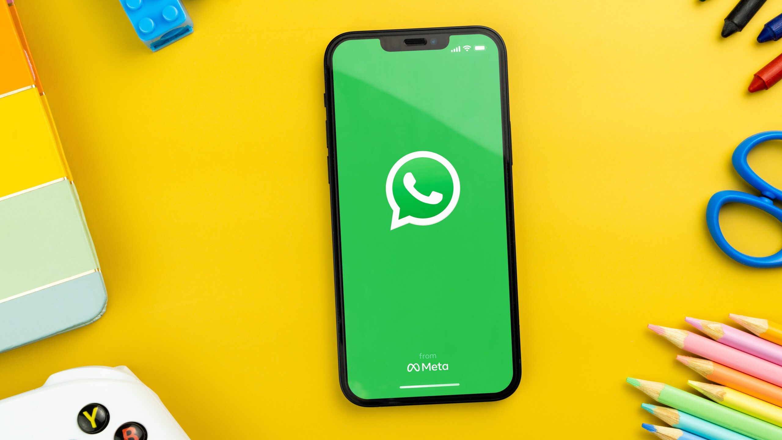 WhatsApp on a yellow desk with colorful accessories
