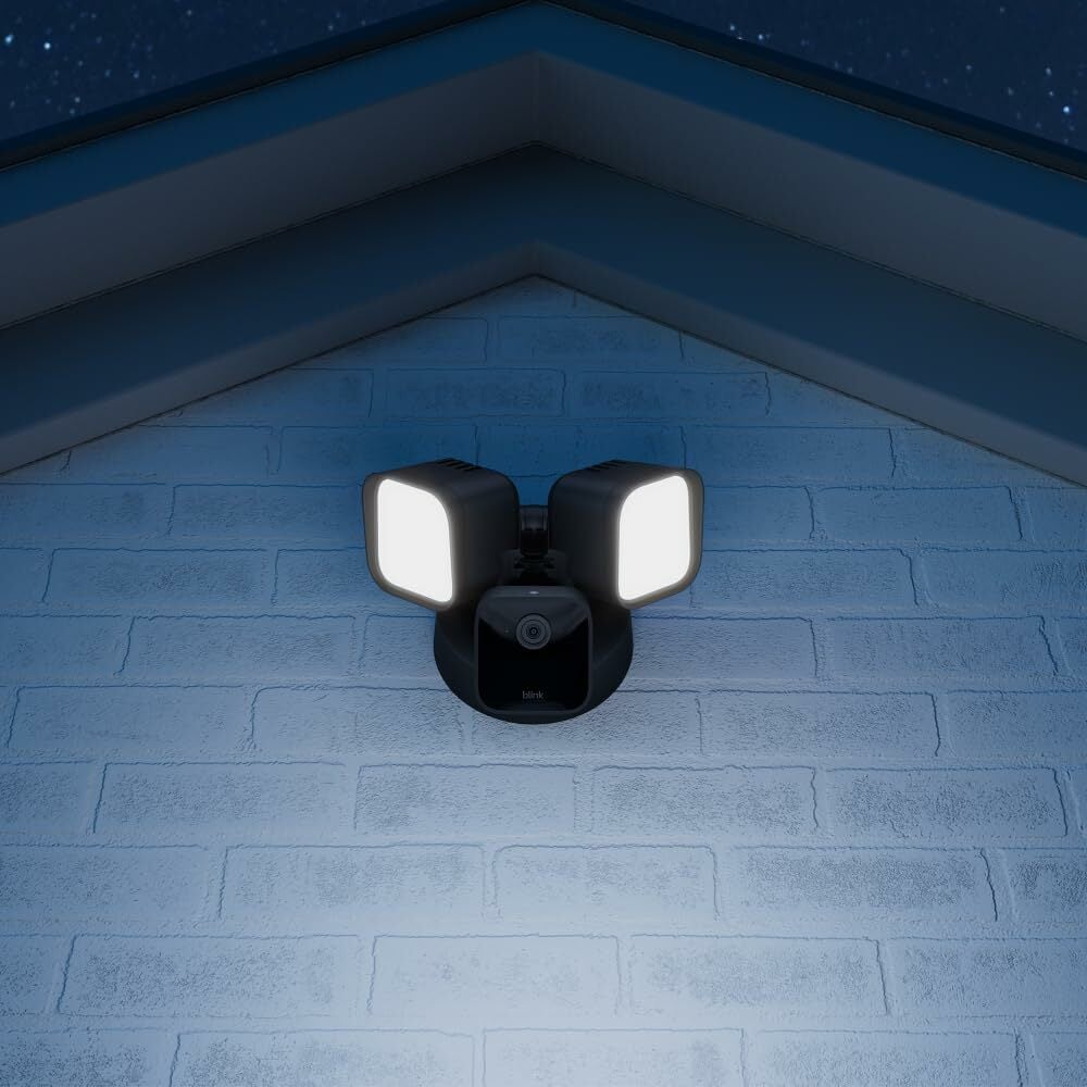 Blink outdoor security camera affixed to home with two floodlights 