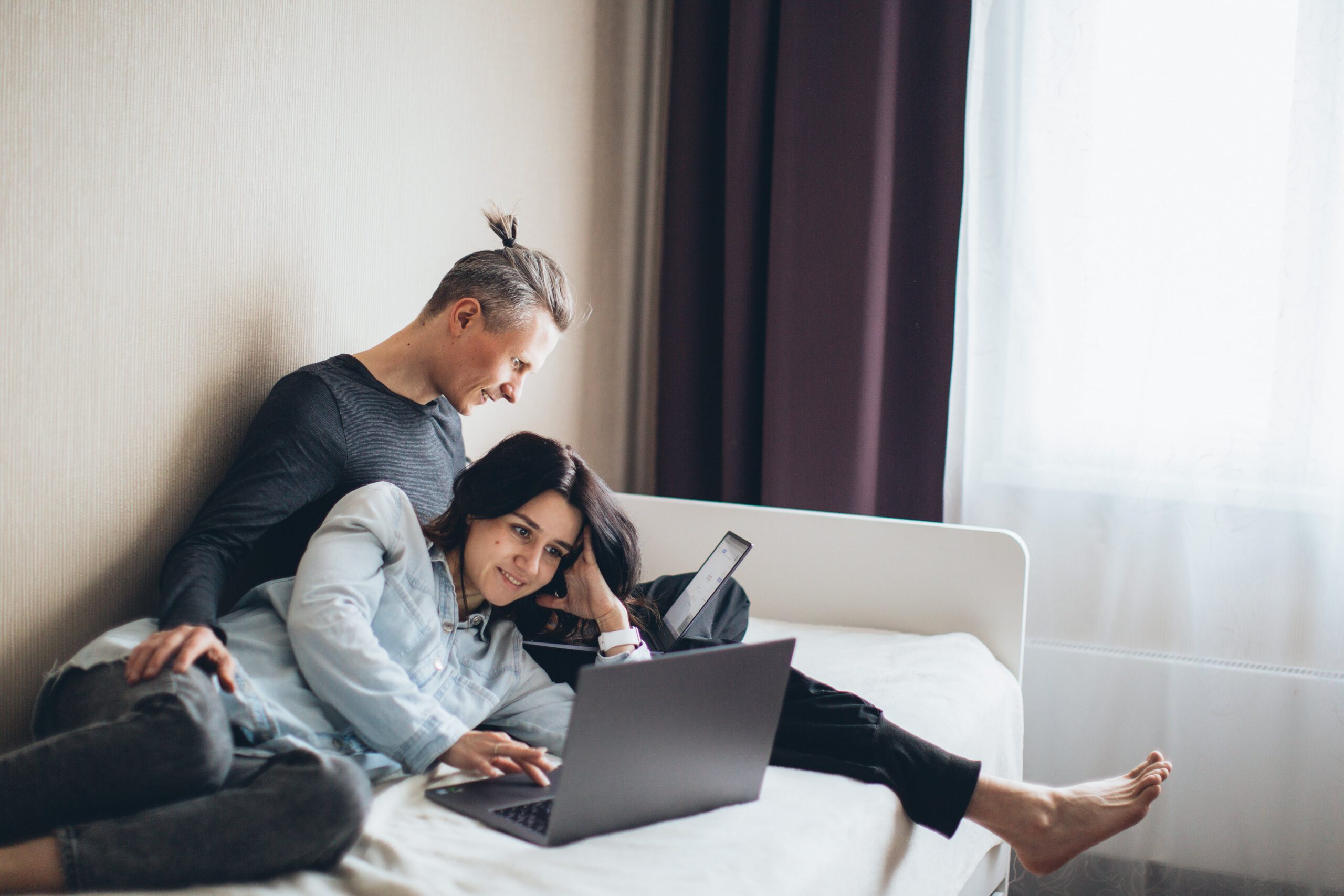 Couple on bed looking at laptop