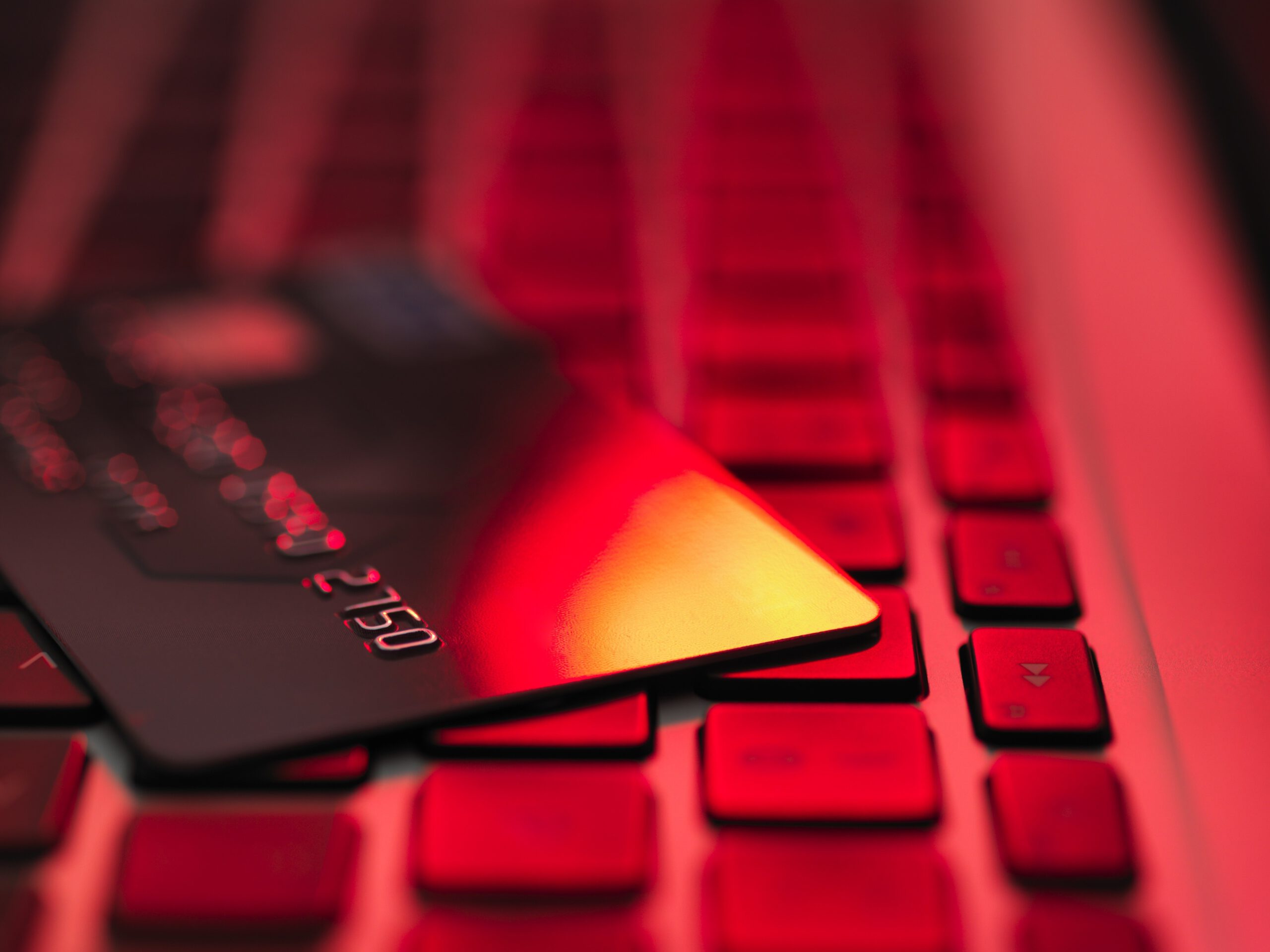 A credit card on a laptop under intense red lighting. 