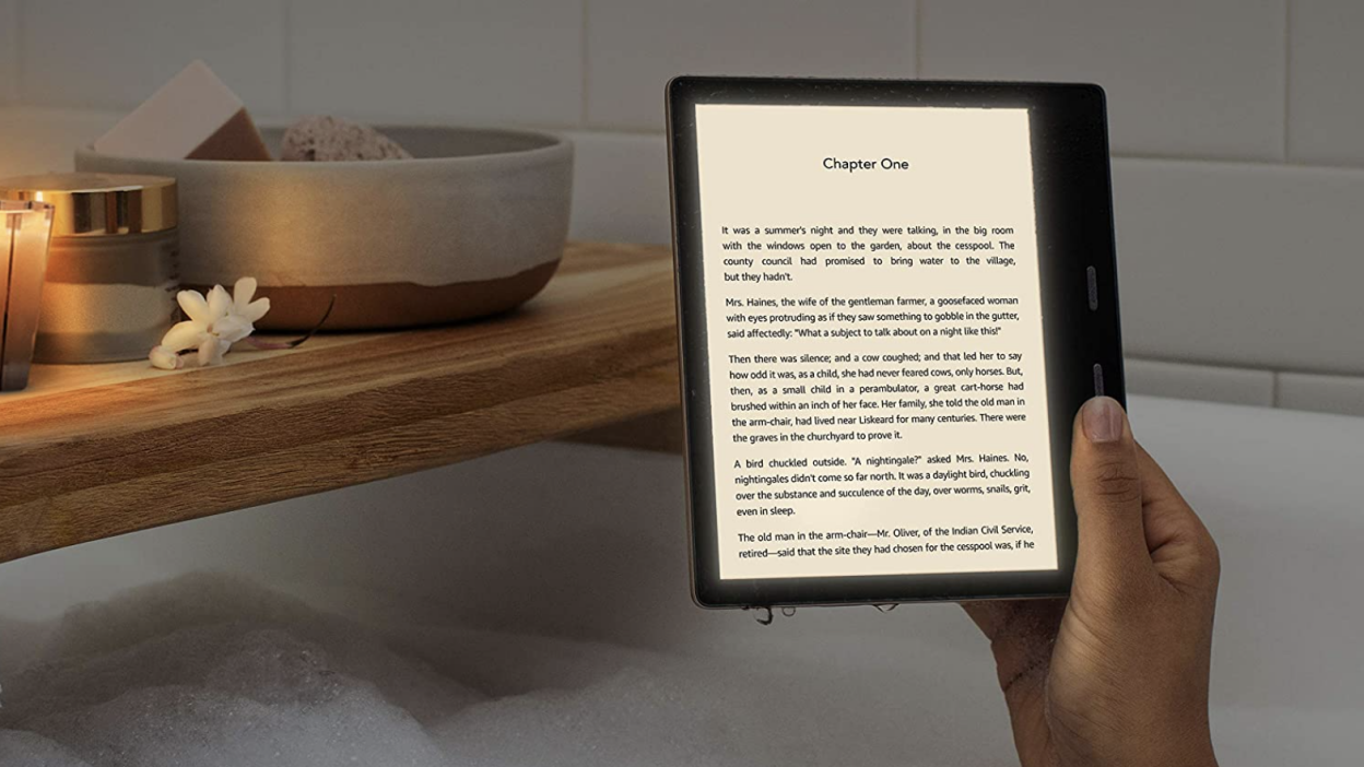 a person holds a kindle oasis with their right hand in the bathtub