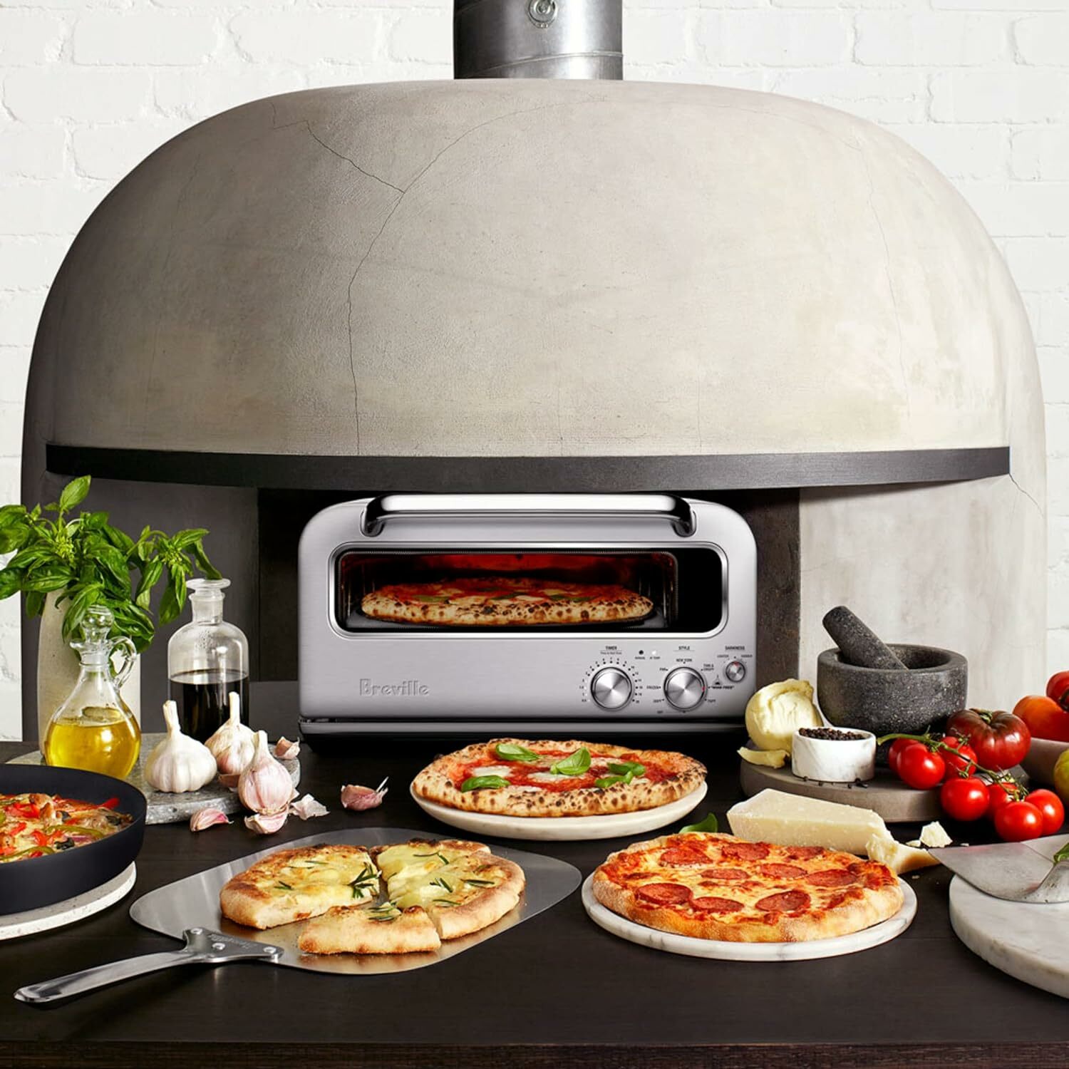 Spread of homemade pizzas in front of Breville pizza oven