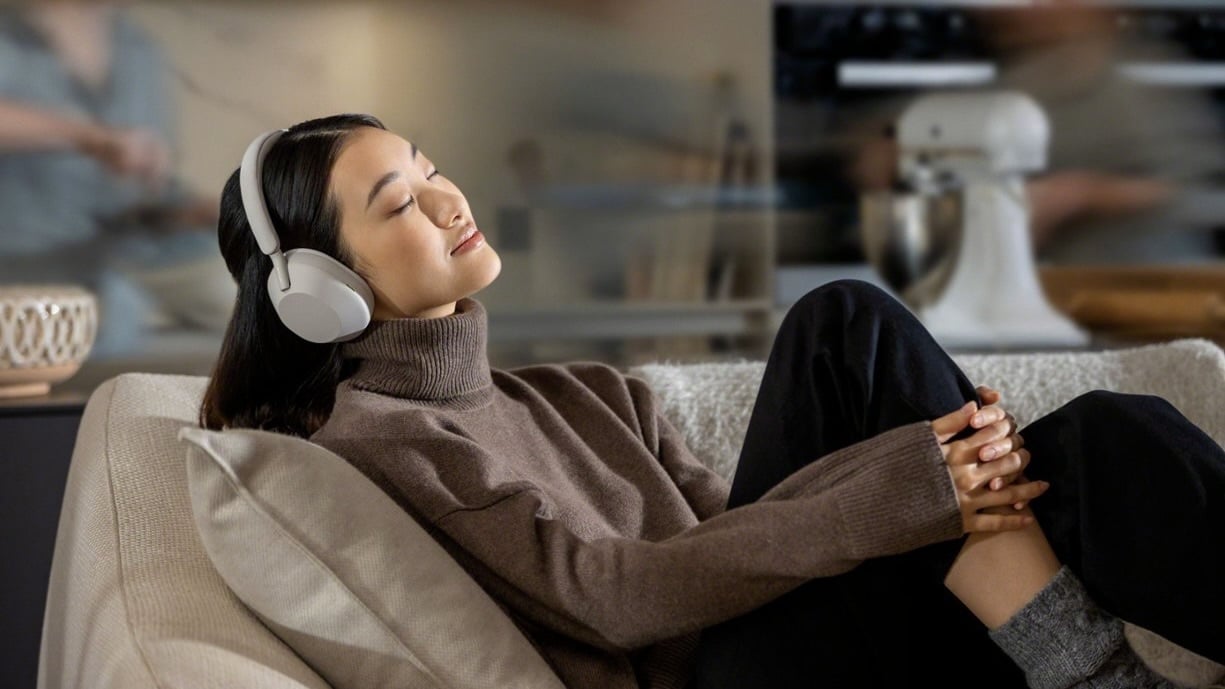 woman laying on couch wearing sony wh-1000xm5 headphones