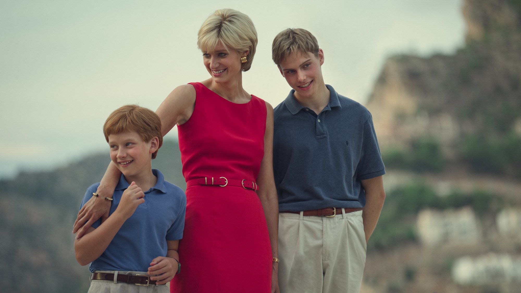 Prince Harry (Luther Ford), Princess Diana (Elizabeth Debicki), and Prince William (Ed McVey) stand together smiling in "The Crown"