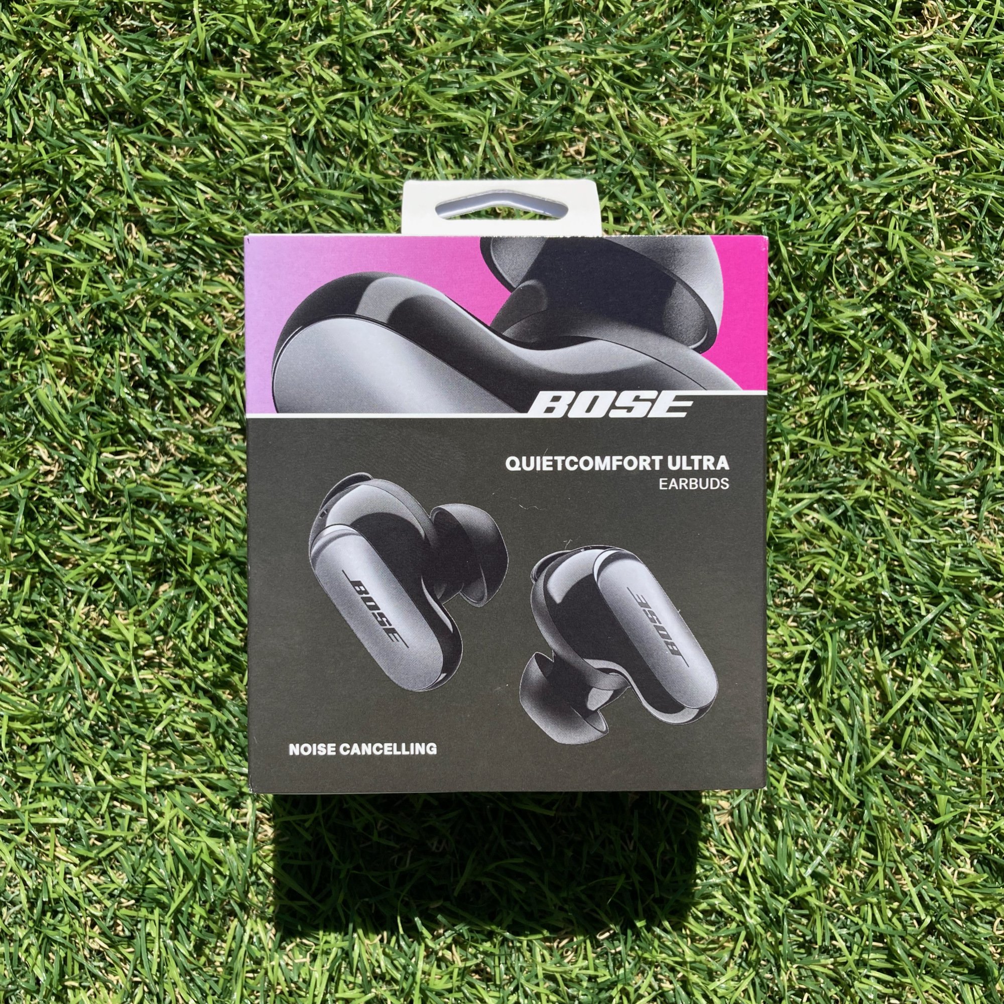 bose quietcomfort ultra earbuds in their packaging on artificial grass