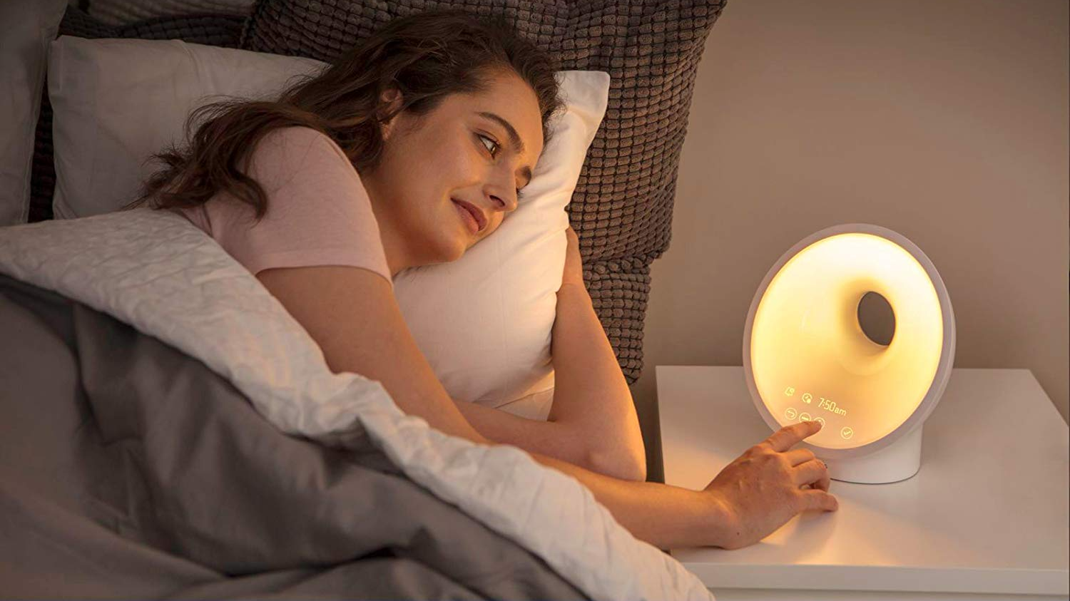 A woman sleeping with a light therapy alarm clock lamp
