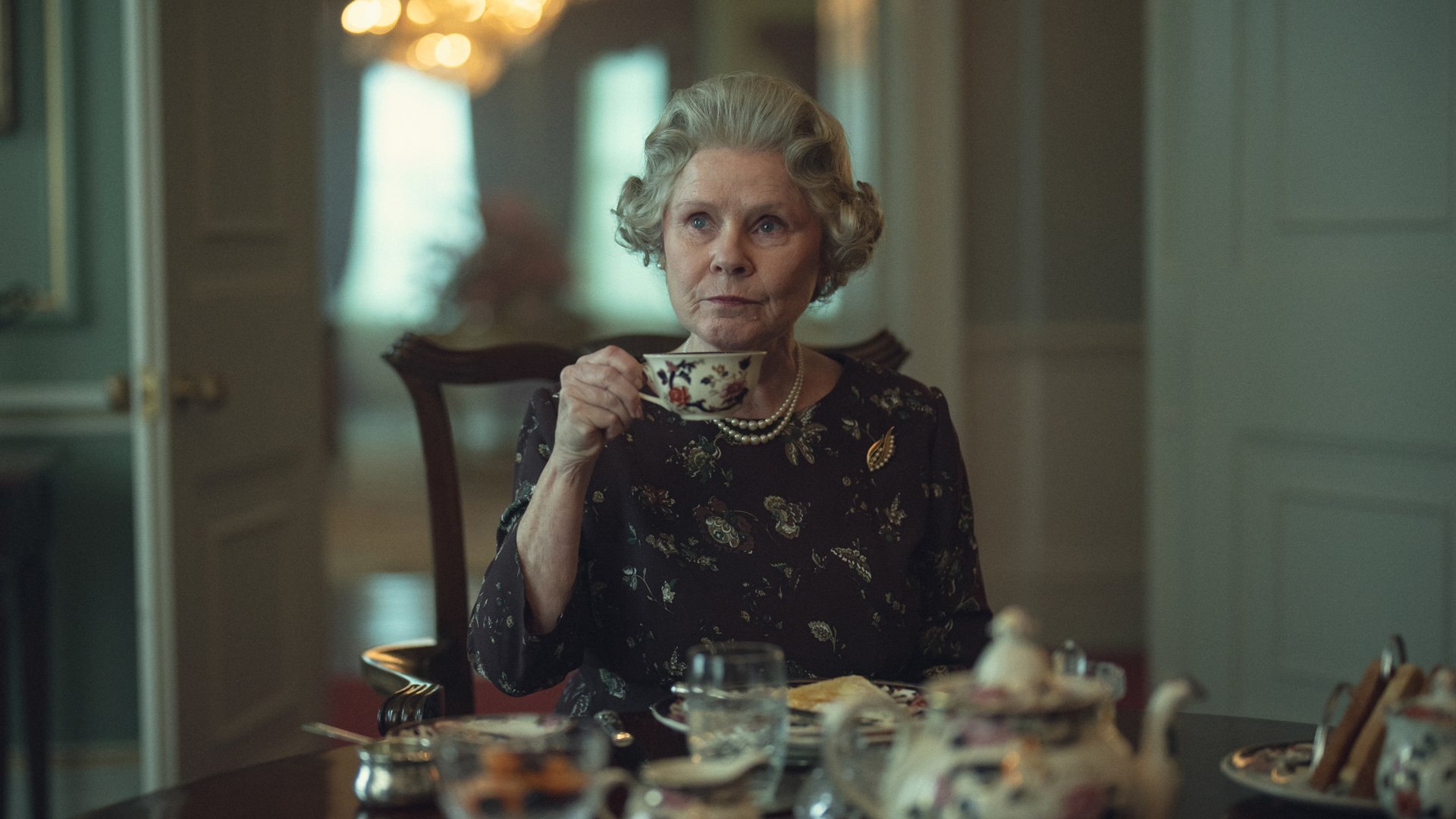 Imelda Staunton as Queen Elizabeth II sitting drinking tea.
