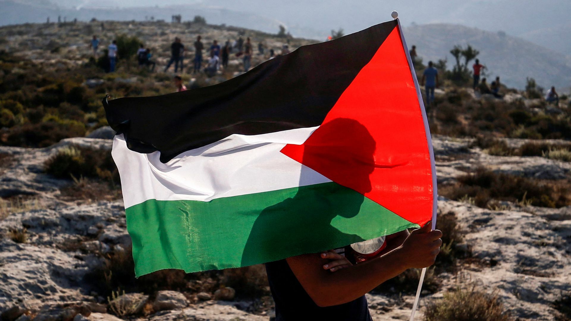 A Palestinian protester waves a Palestinian flag during a demonstration in the village of Ras Karkar west of Ramallah.