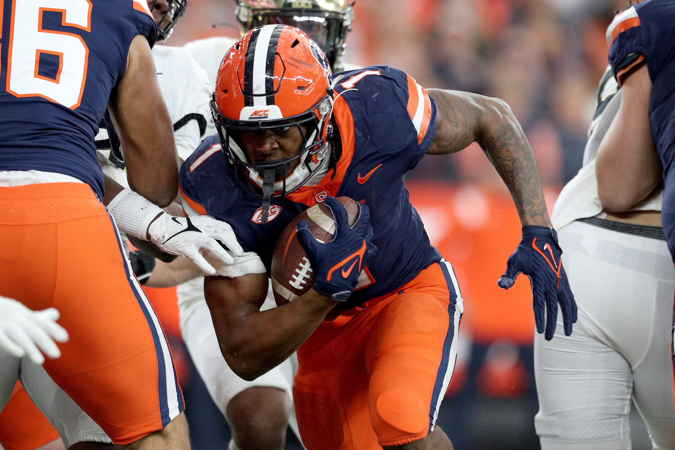 A Syracuse player carrying the football into a group of defenders.