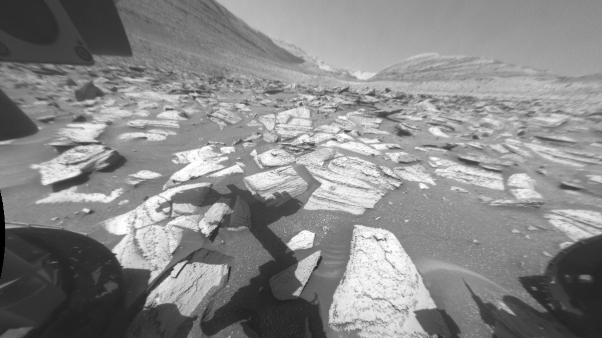 A Martian landscape taken by the Curiosity Rover, whose shadow is in the foreground.
